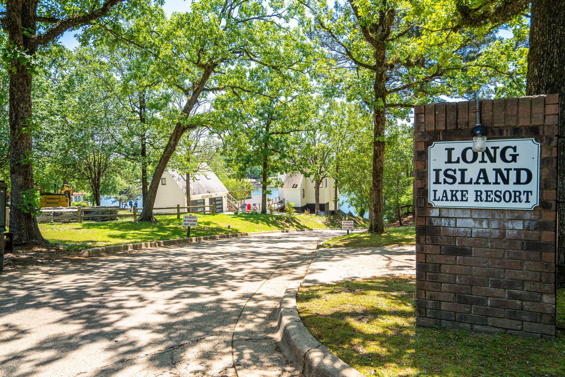 A sign for long island lake resort is on a brick wall.