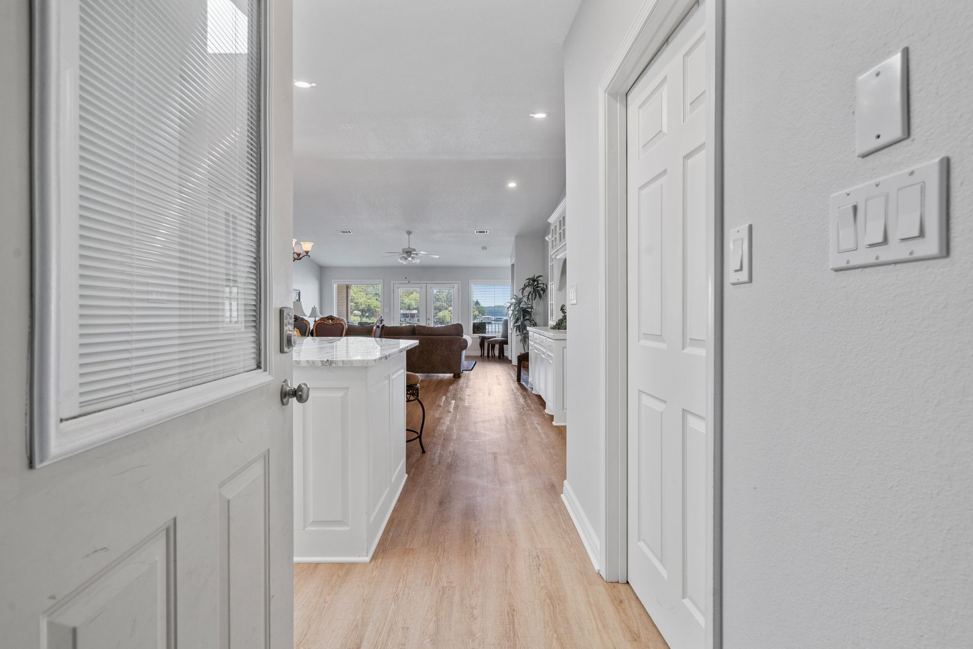 A hallway in a house leading to a living room and kitchen.