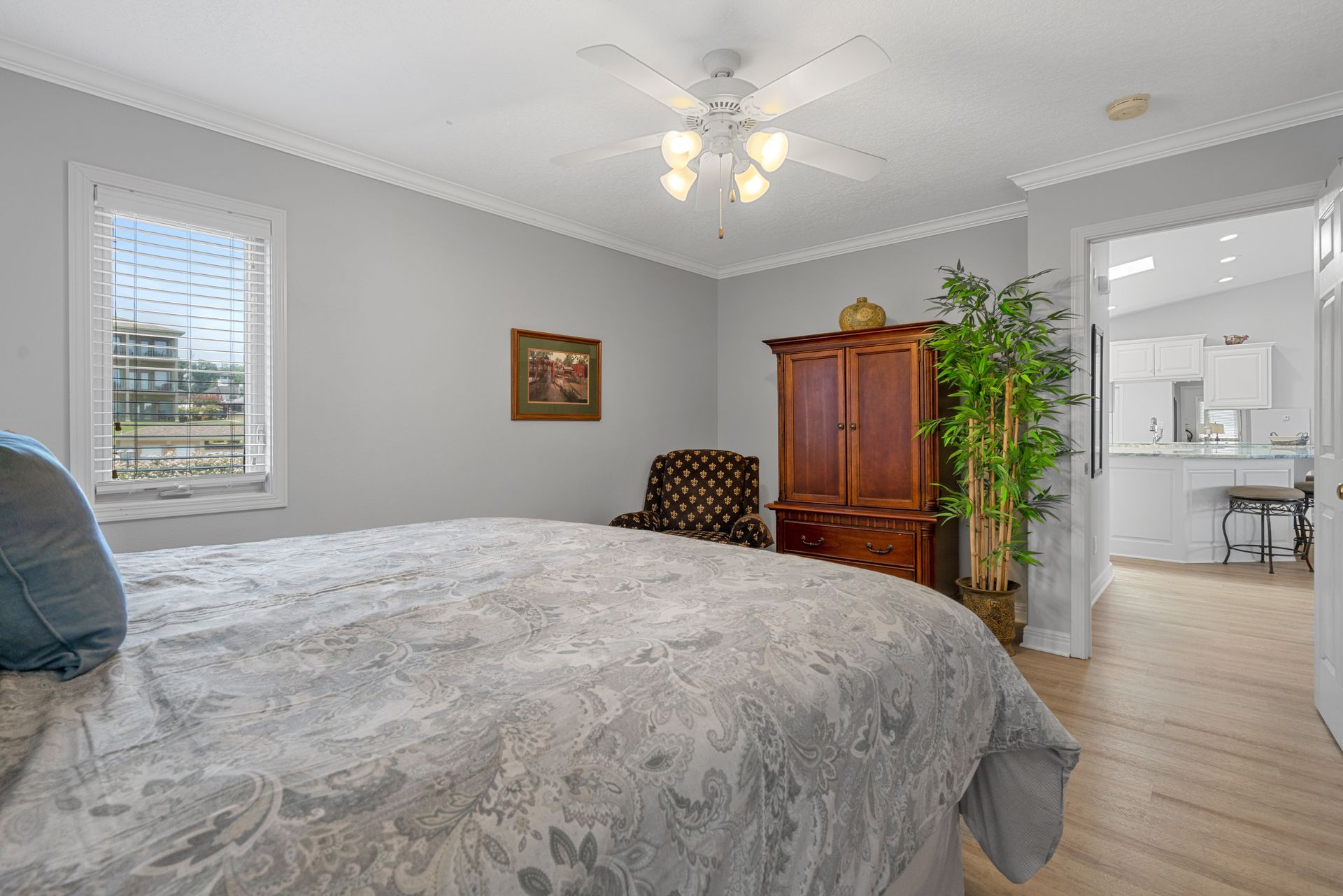 A bedroom with a bed , chair , cabinet and ceiling fan.