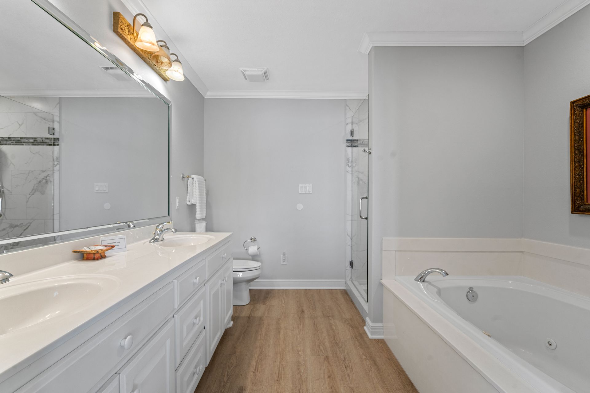 A bathroom with two sinks , a tub , a toilet and a mirror.