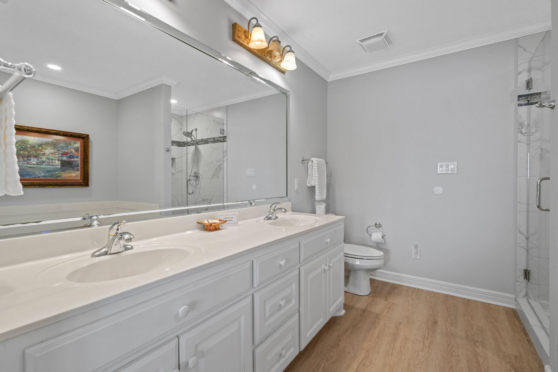 A bathroom with two sinks , a toilet , and a large mirror.
