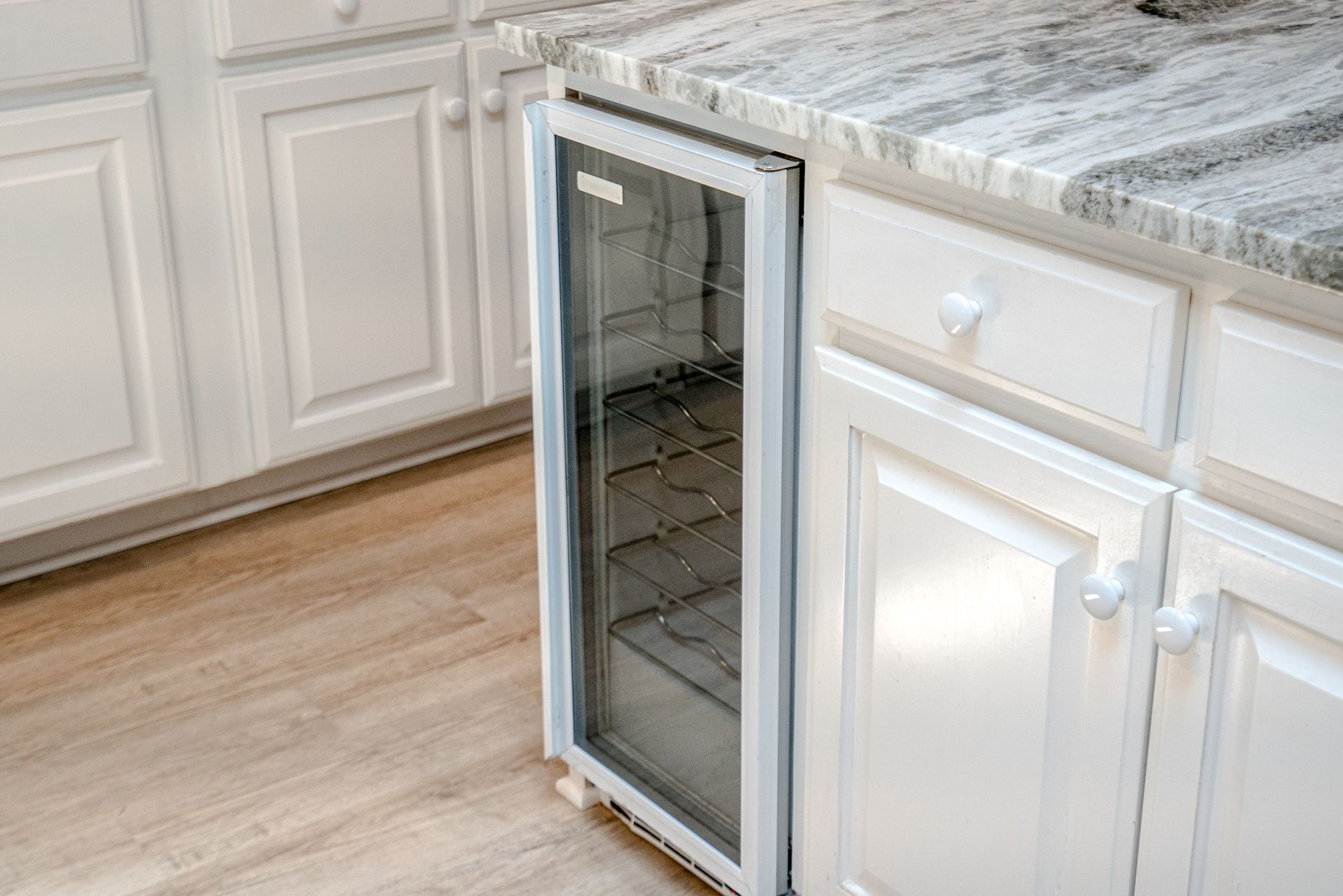 A small refrigerator is sitting on a counter in a kitchen.