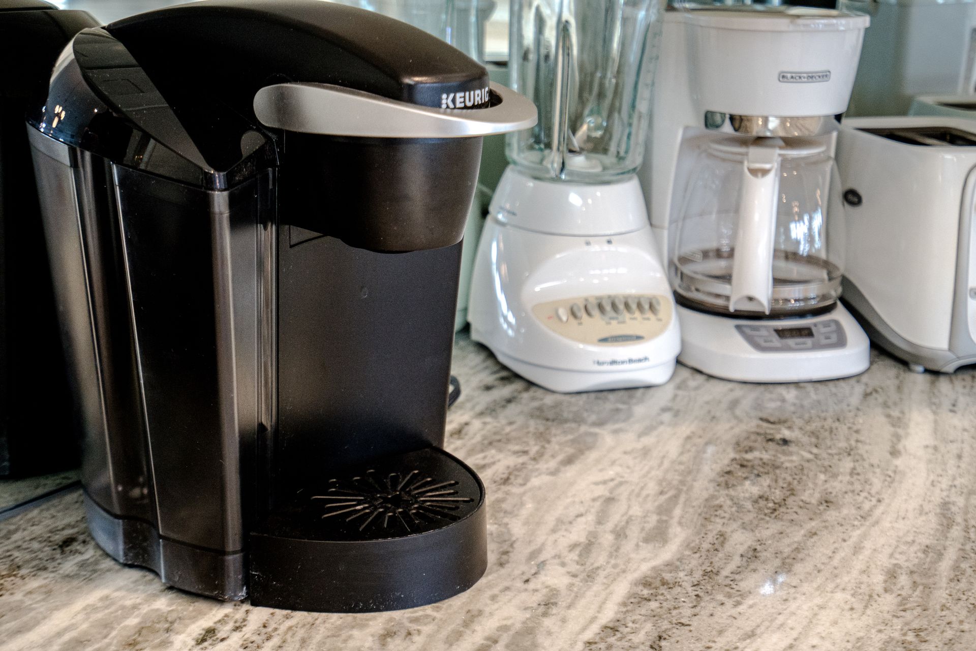 A keurig coffee maker sits on a counter next to a blender and toaster