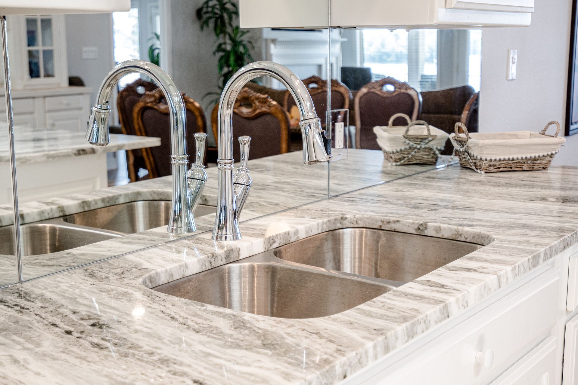 A kitchen with a sink and faucets on a granite counter top.