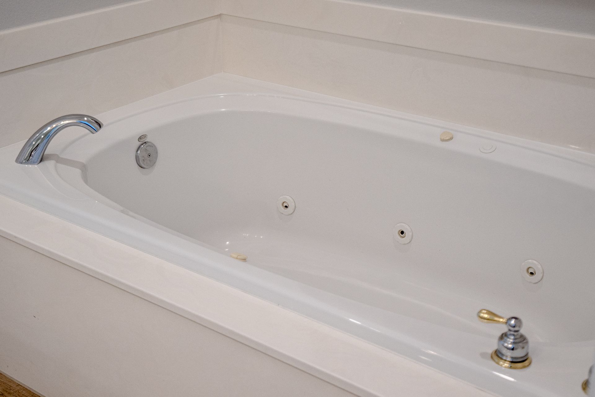 A white jacuzzi tub with chrome handles in a bathroom.