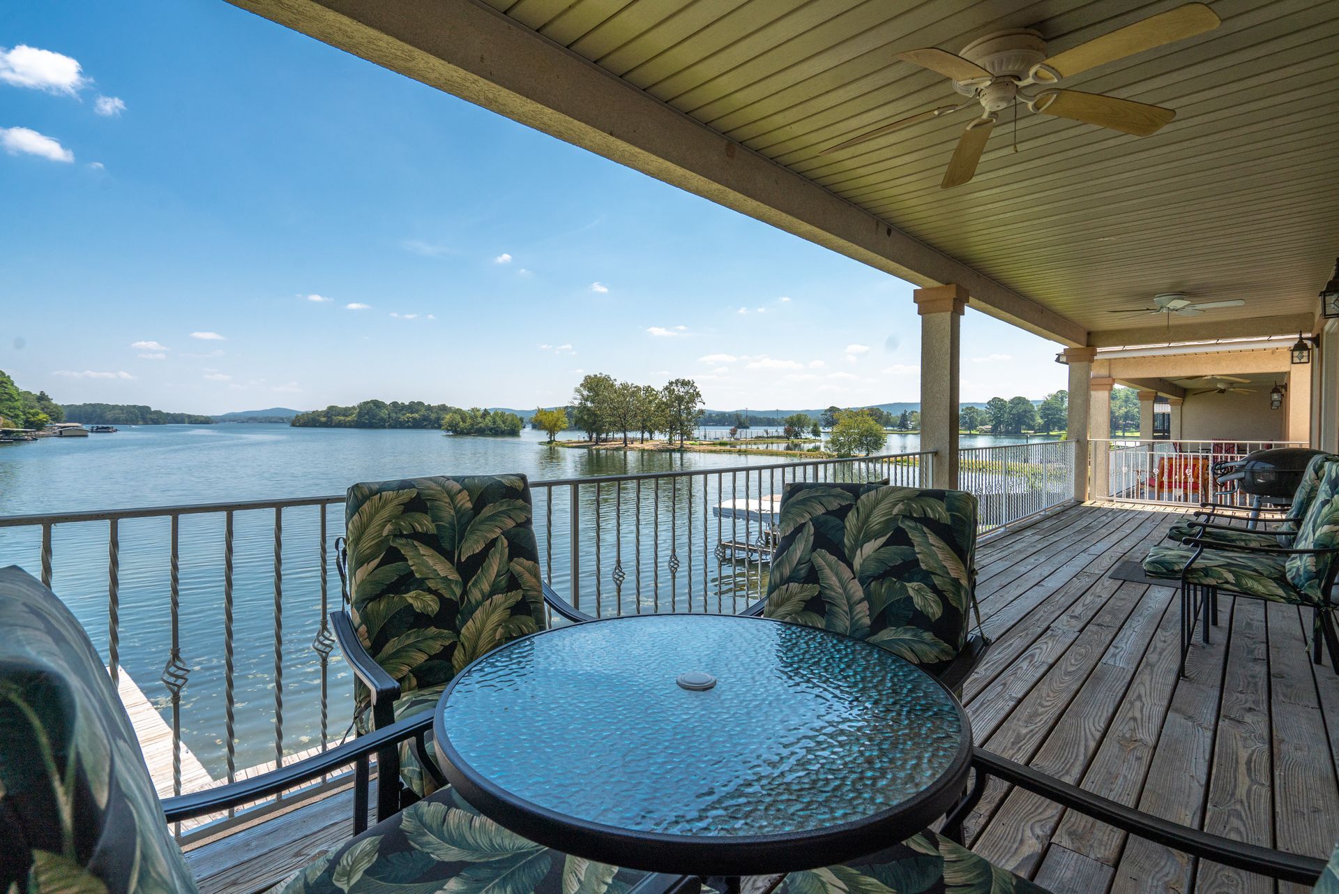 A deck with a table and chairs overlooking a lake.