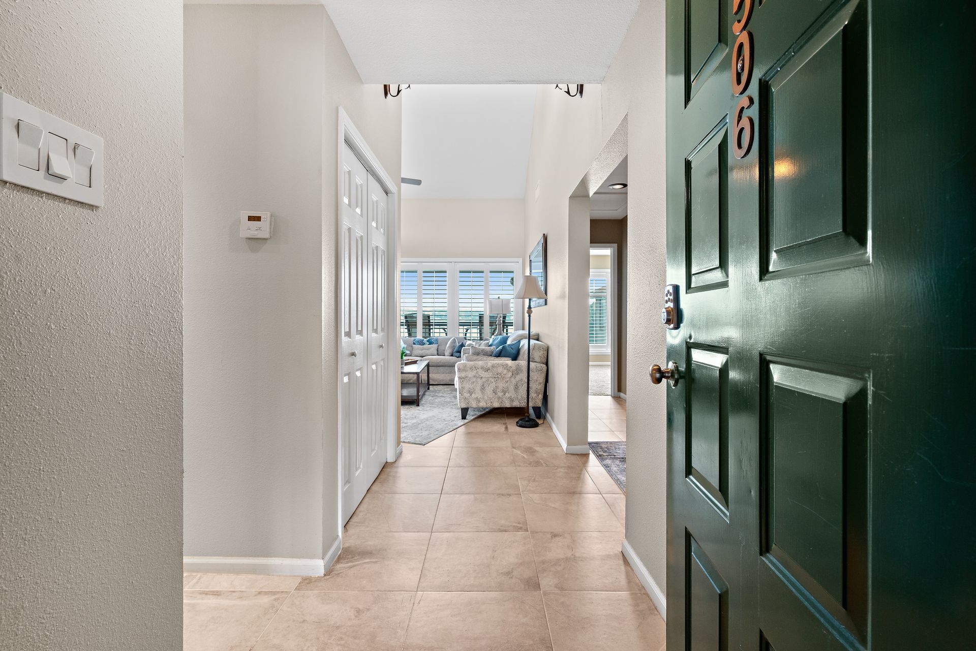 A hallway with a green door leading to a living room.