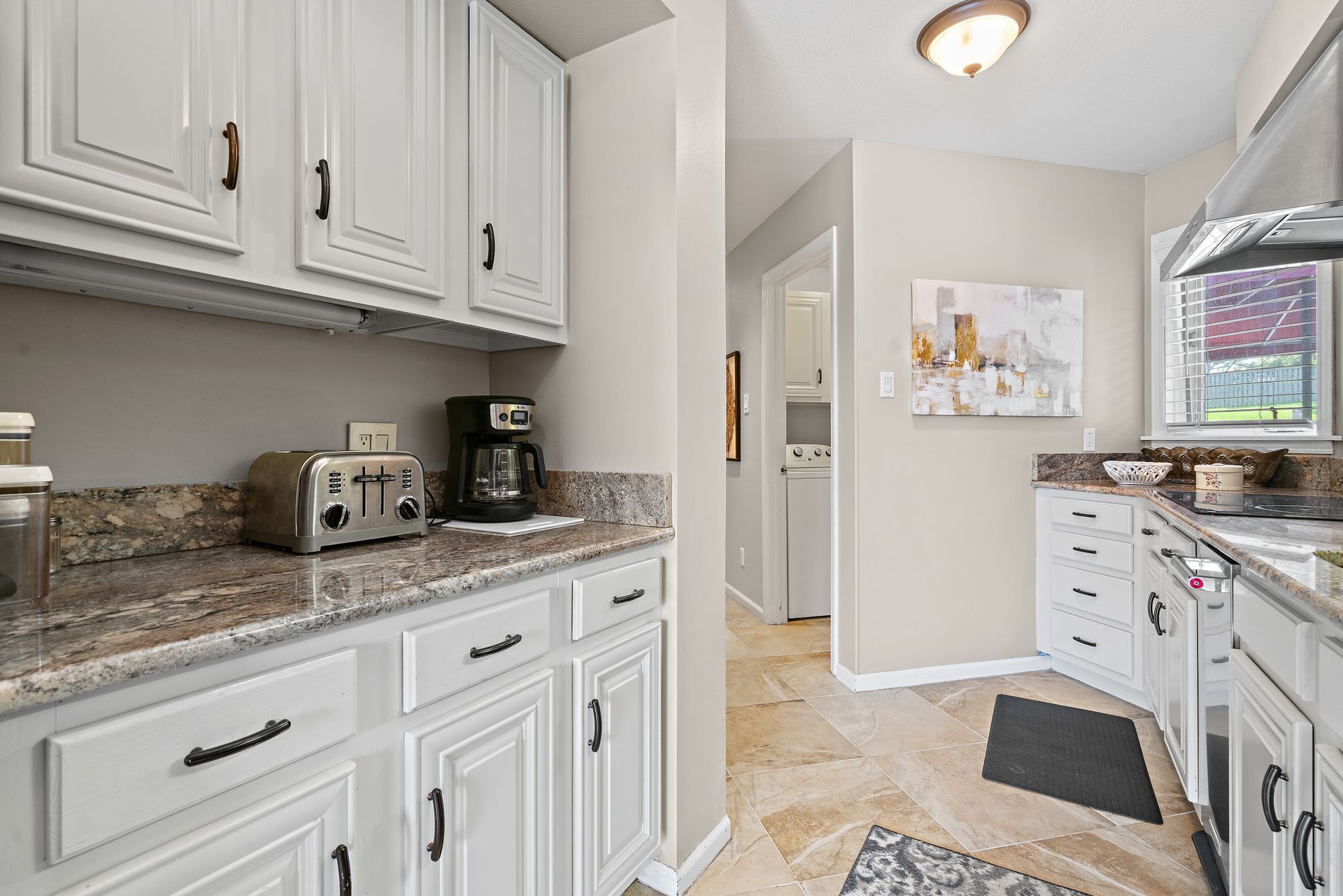 A kitchen with white cabinets and granite counter tops.