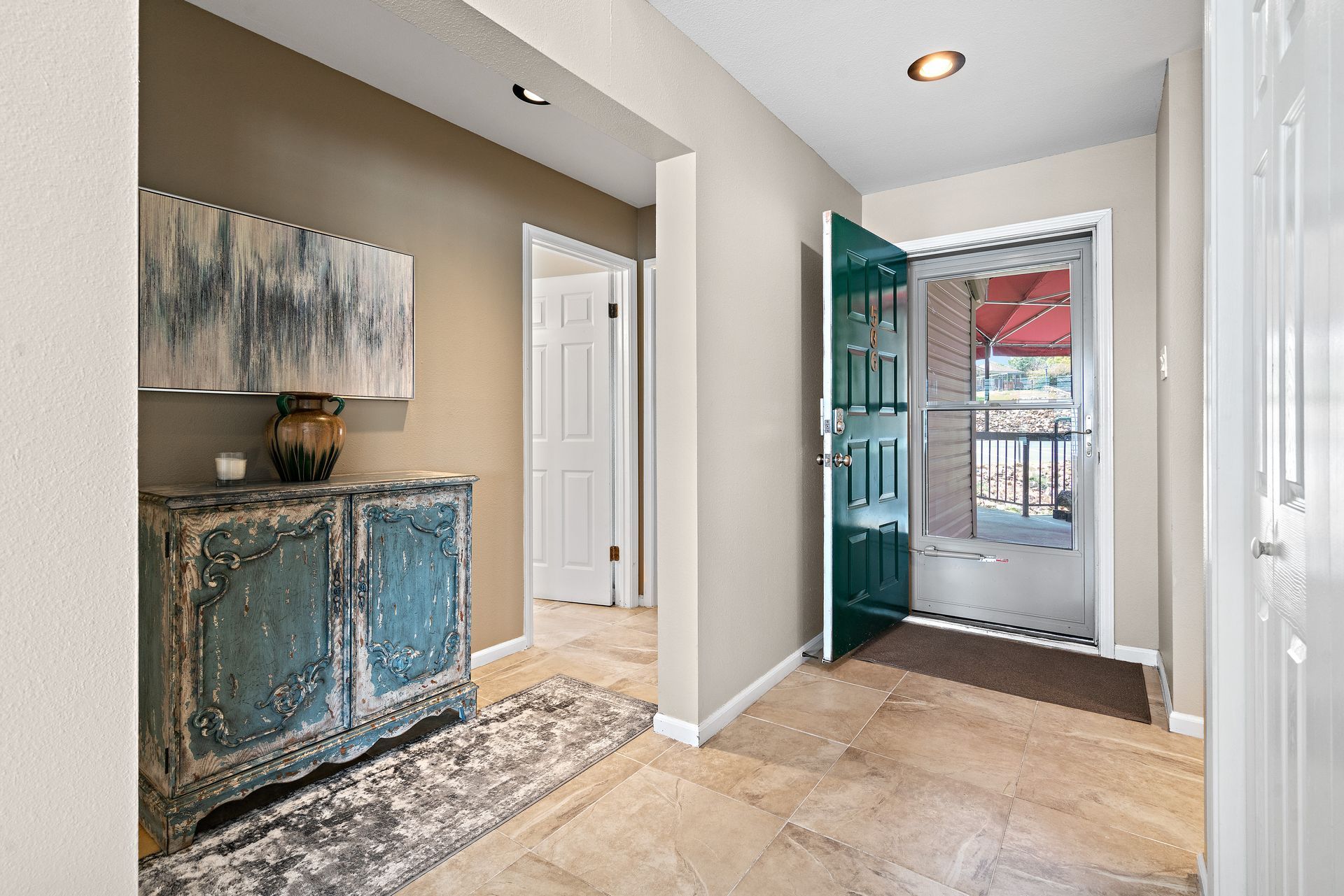 A hallway in a house with a blue door and a dresser.