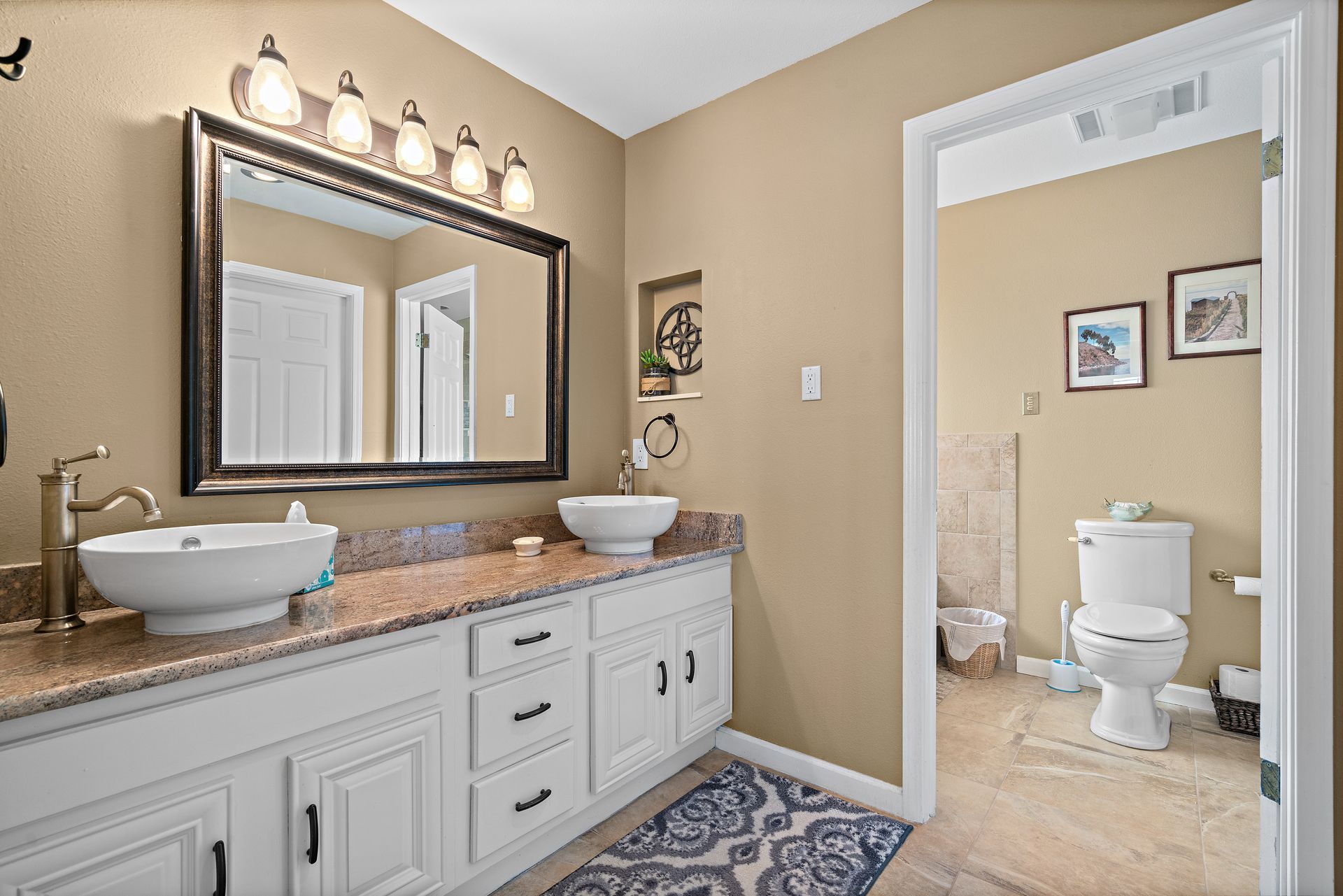 A bathroom with two sinks , a toilet and a mirror.