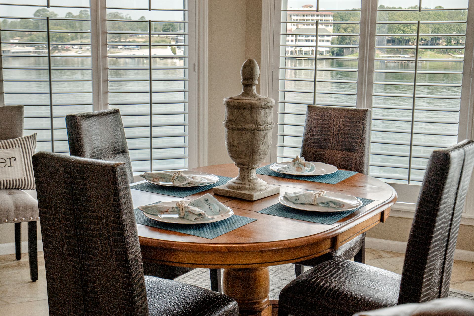 A dining room with a table and chairs and a view of the water.
