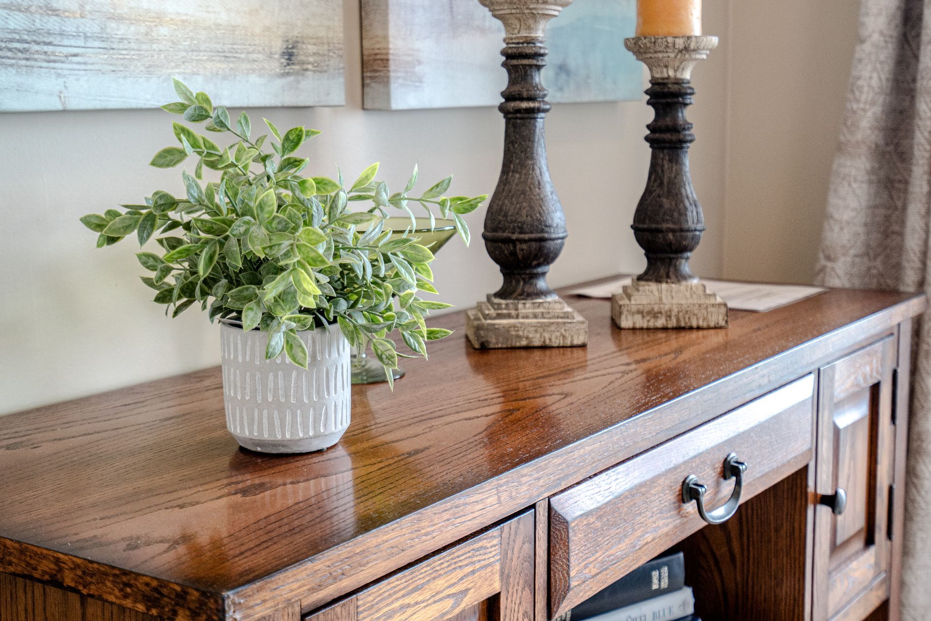 A wooden table with two candles and a potted plant on it.