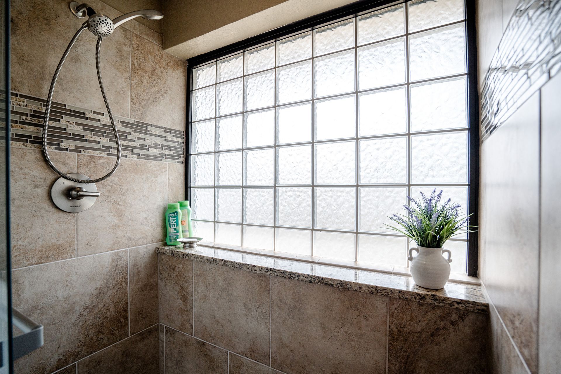 A bathroom with a shower and a window with glass blocks.