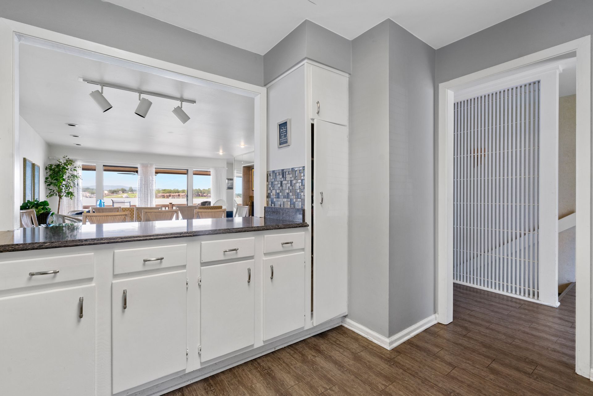 A kitchen with white cabinets , granite counter tops , and hardwood floors.