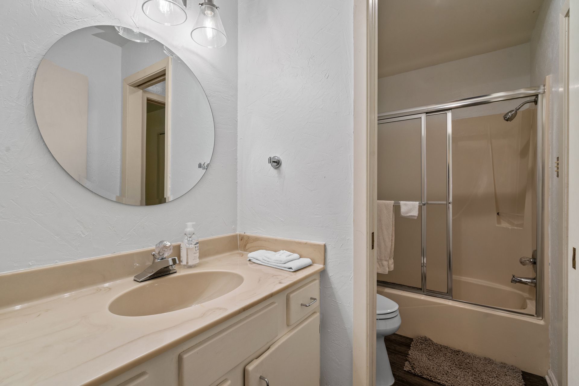 A bathroom with a sink , toilet , shower and mirror.