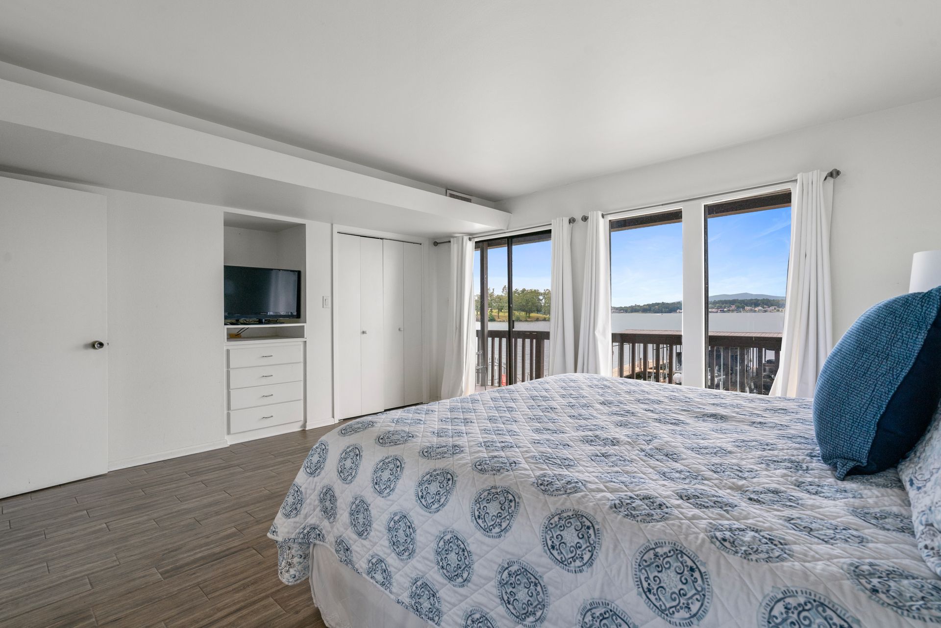 A bedroom with a king size bed , a television , and a balcony.