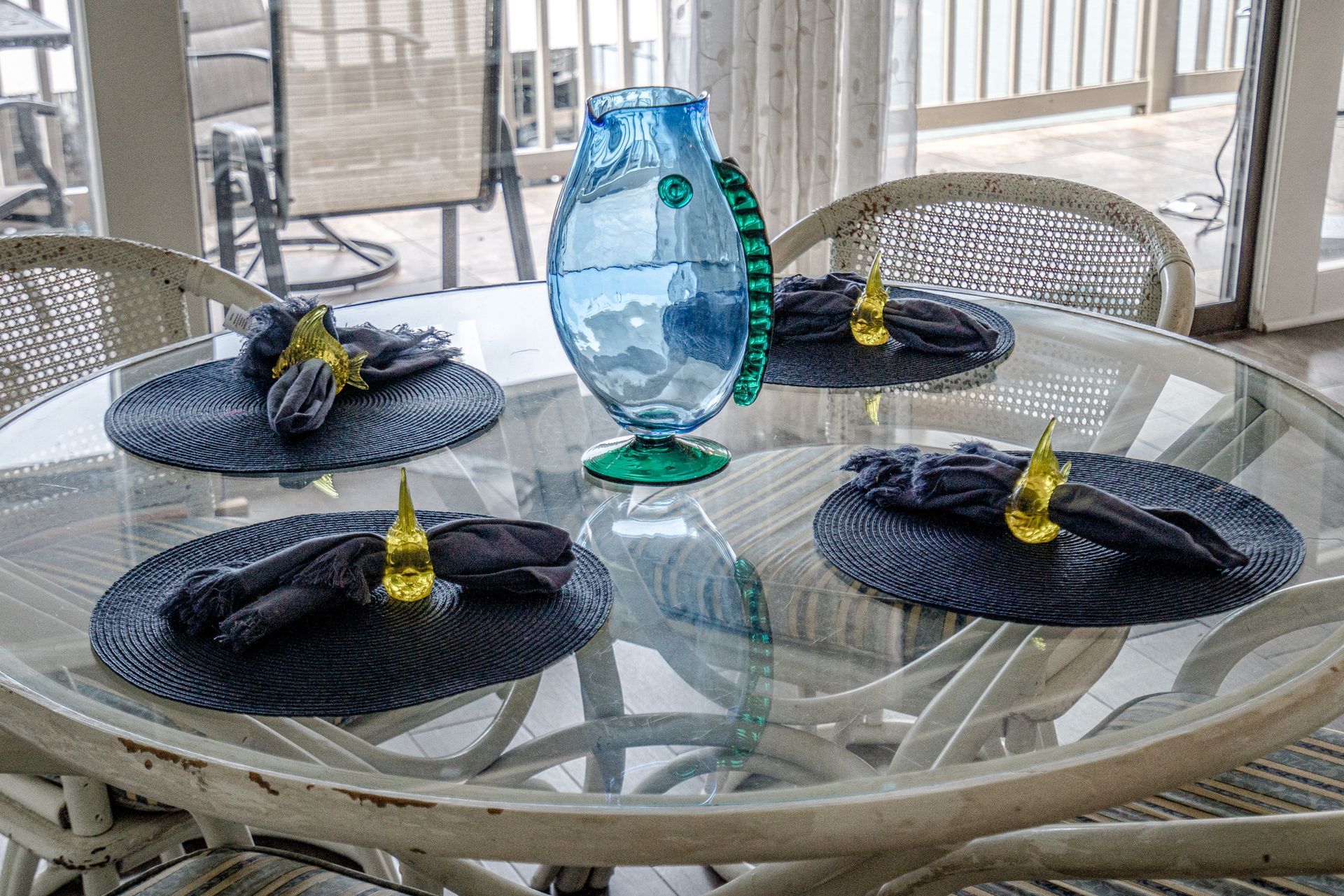 A dining table with plates , napkins and a vase on it.