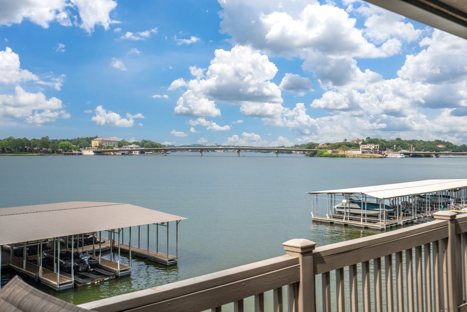 A view of a lake from a balcony with boats docked in the water.