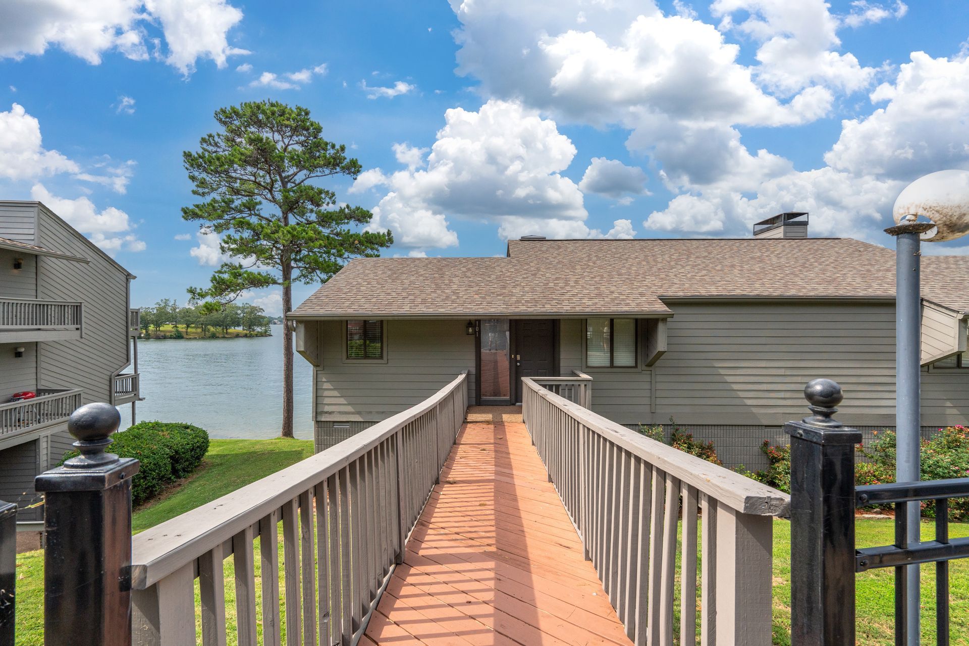 A wooden walkway leading to a house with a lake in the background.