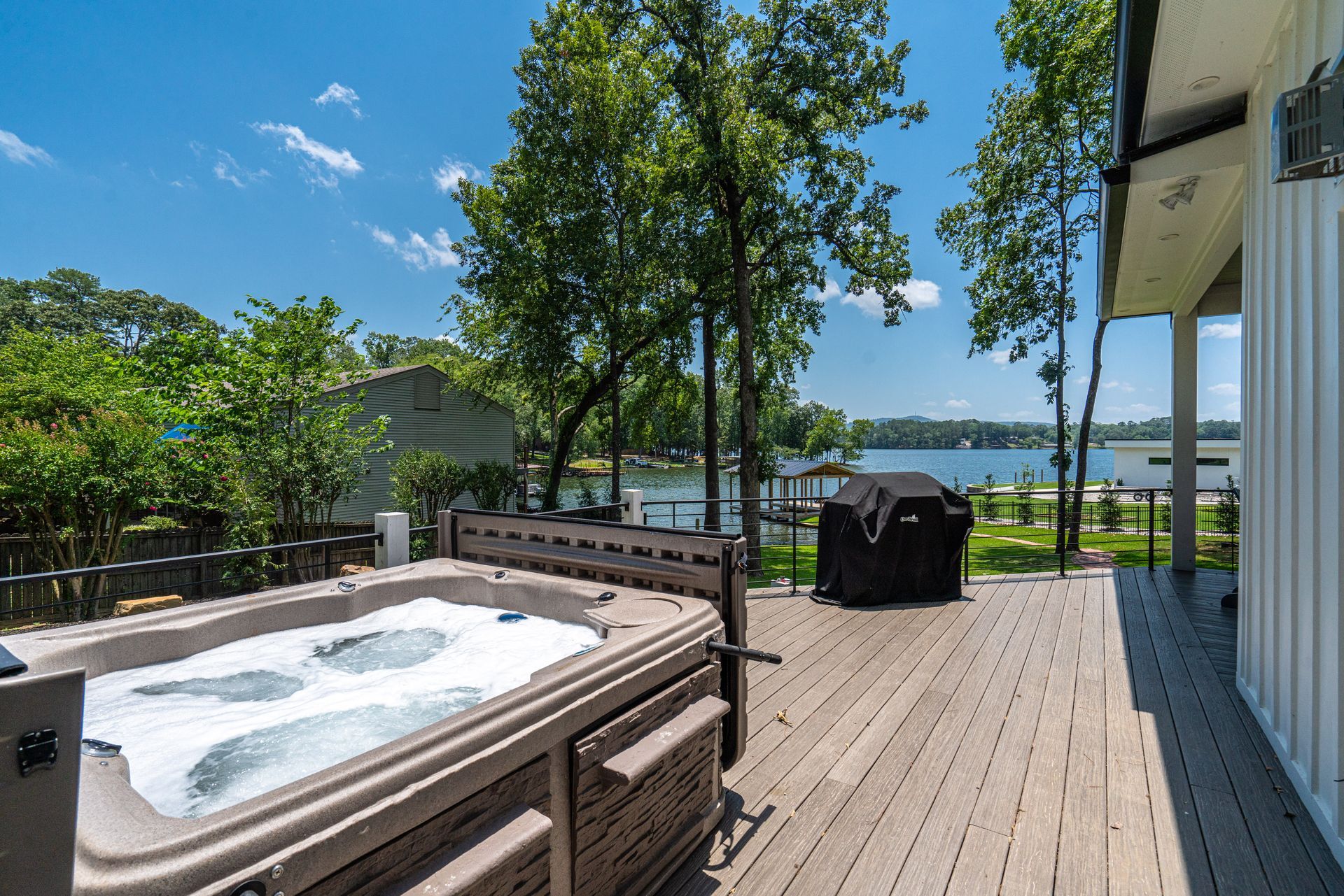 A hot tub is sitting on a wooden deck overlooking a lake.