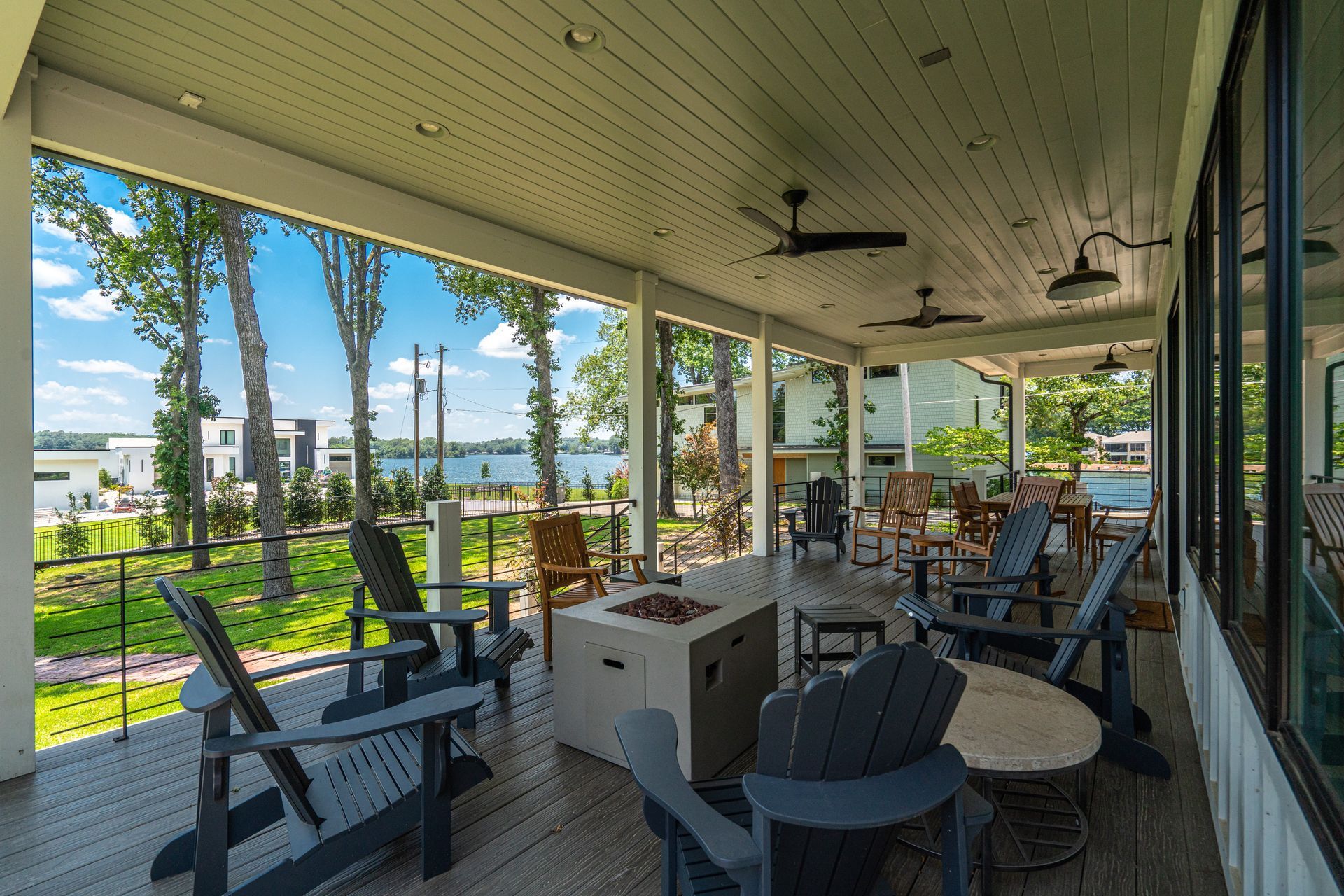 A large porch with chairs , tables , and a fire pit.