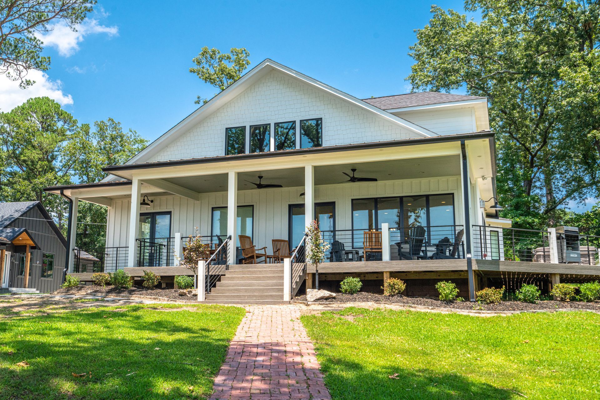 A large white house with a large porch and a brick walkway leading to it.