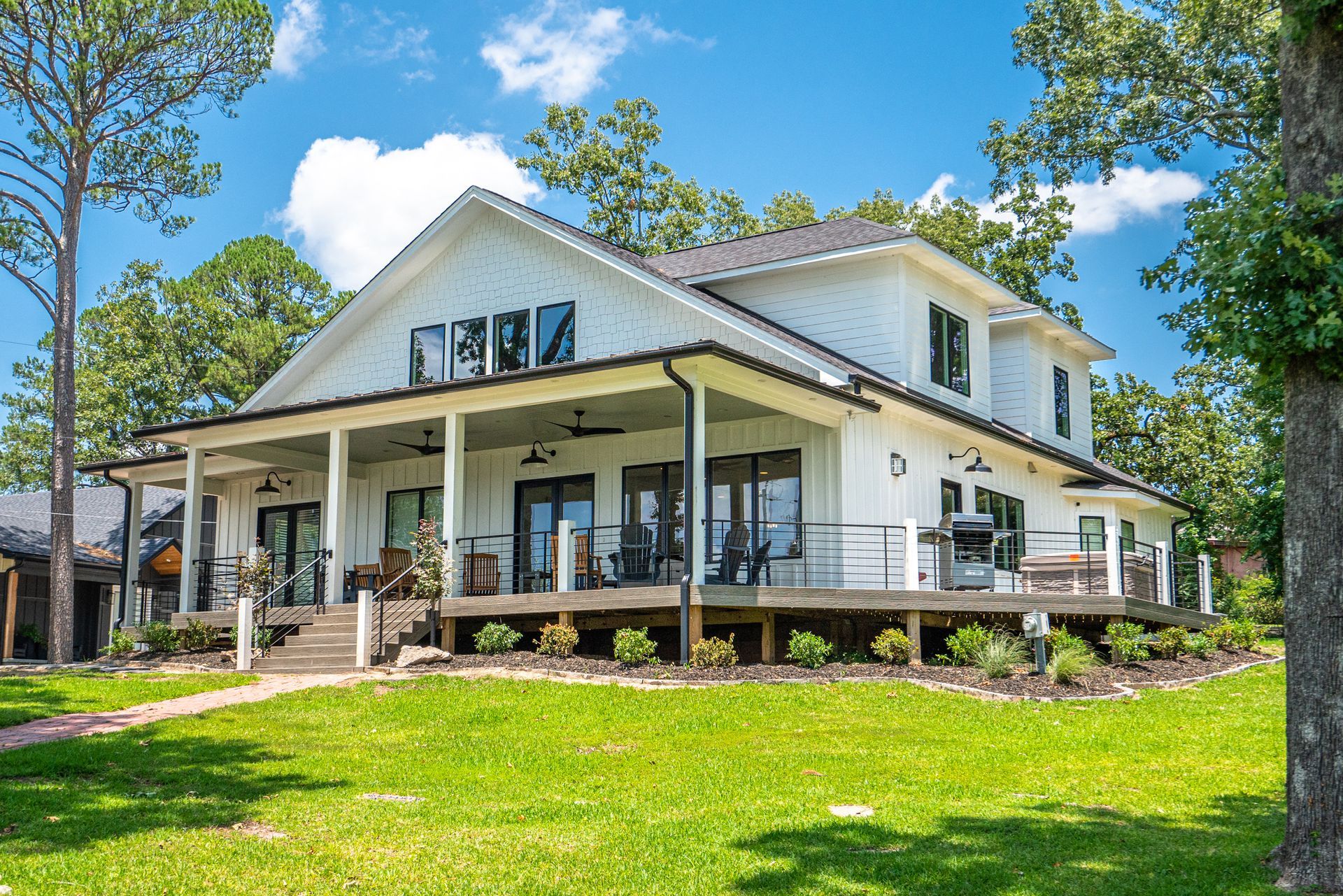 A large white house with a large porch is sitting on top of a lush green hill.