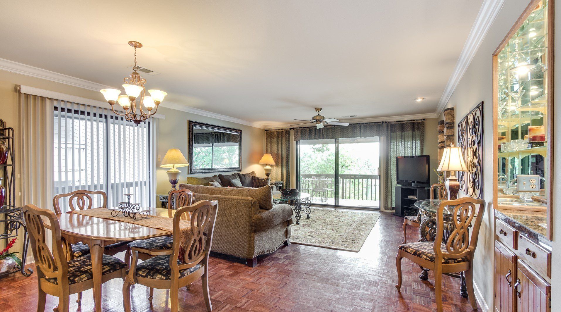 A living room with a dining table , chairs , a couch and a television.