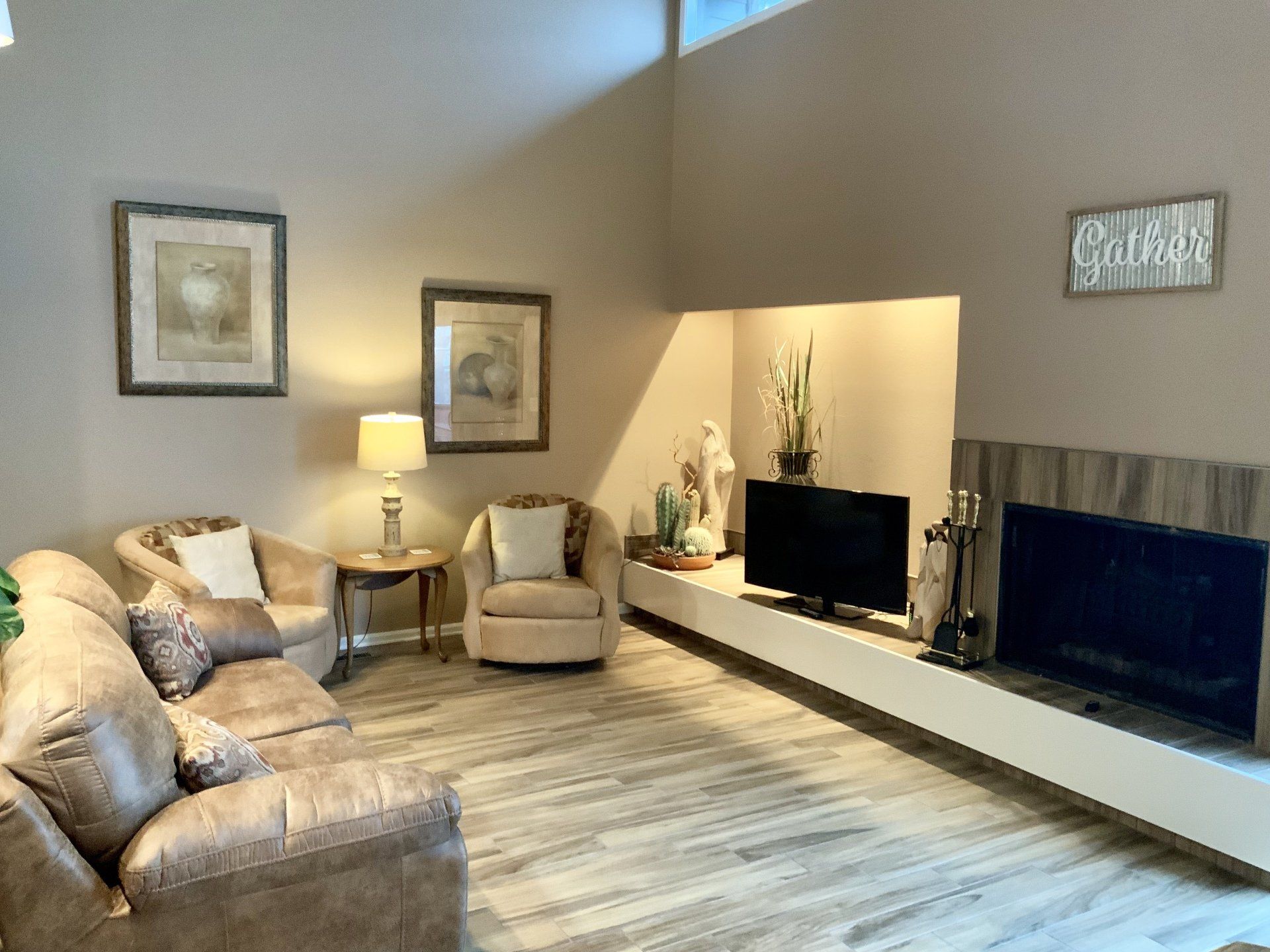 A living room with a couch , chair , television and fireplace.