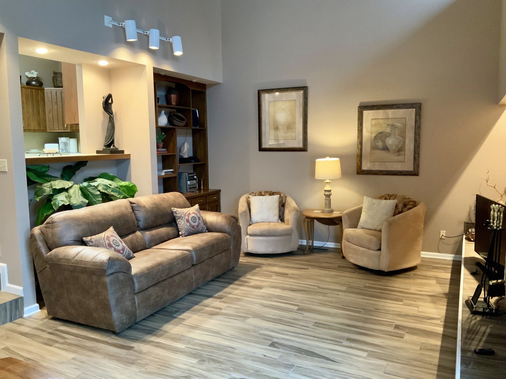 A living room with a couch , two chairs and a television.