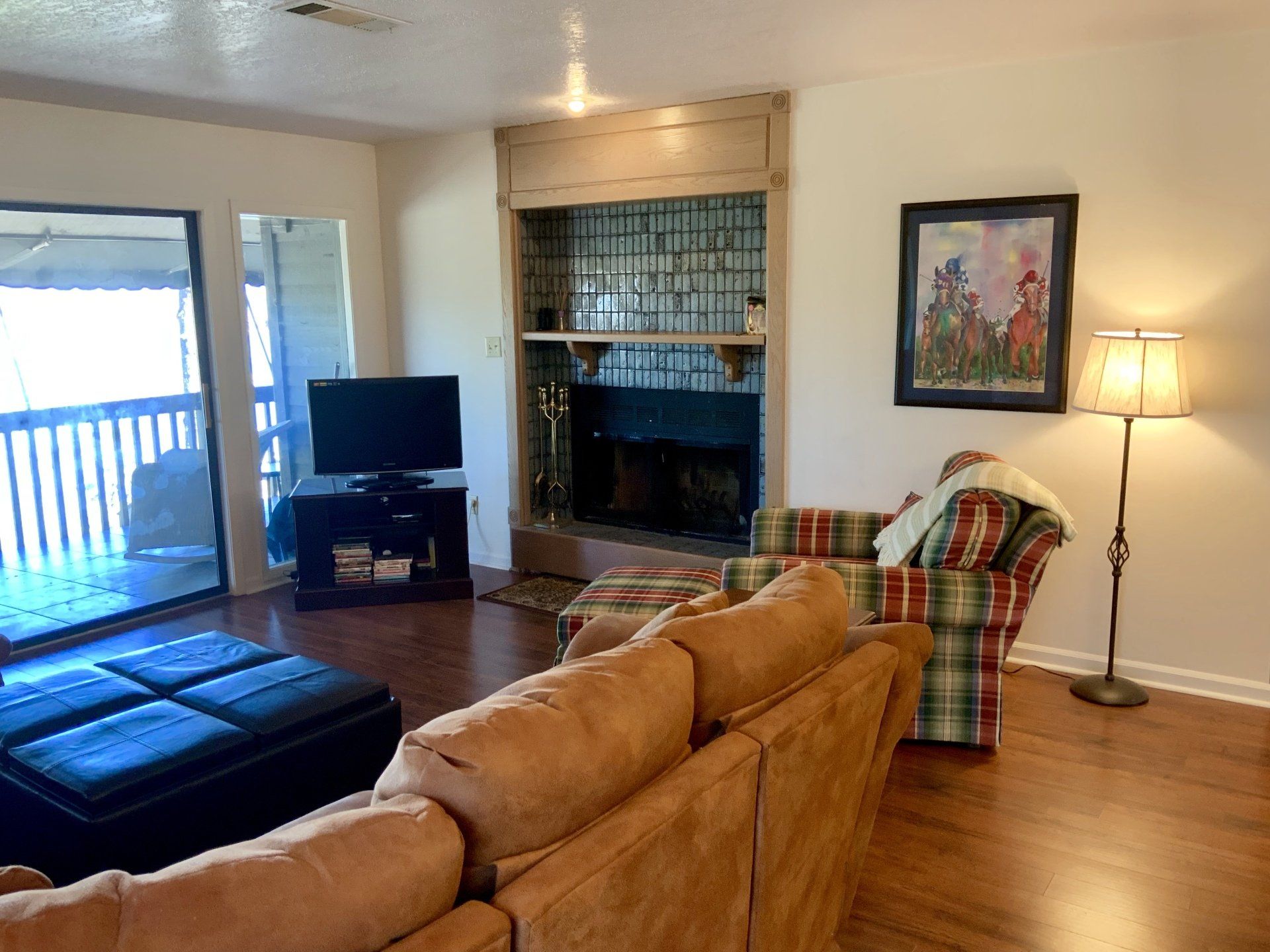 A living room with a couch , chair , television and fireplace.