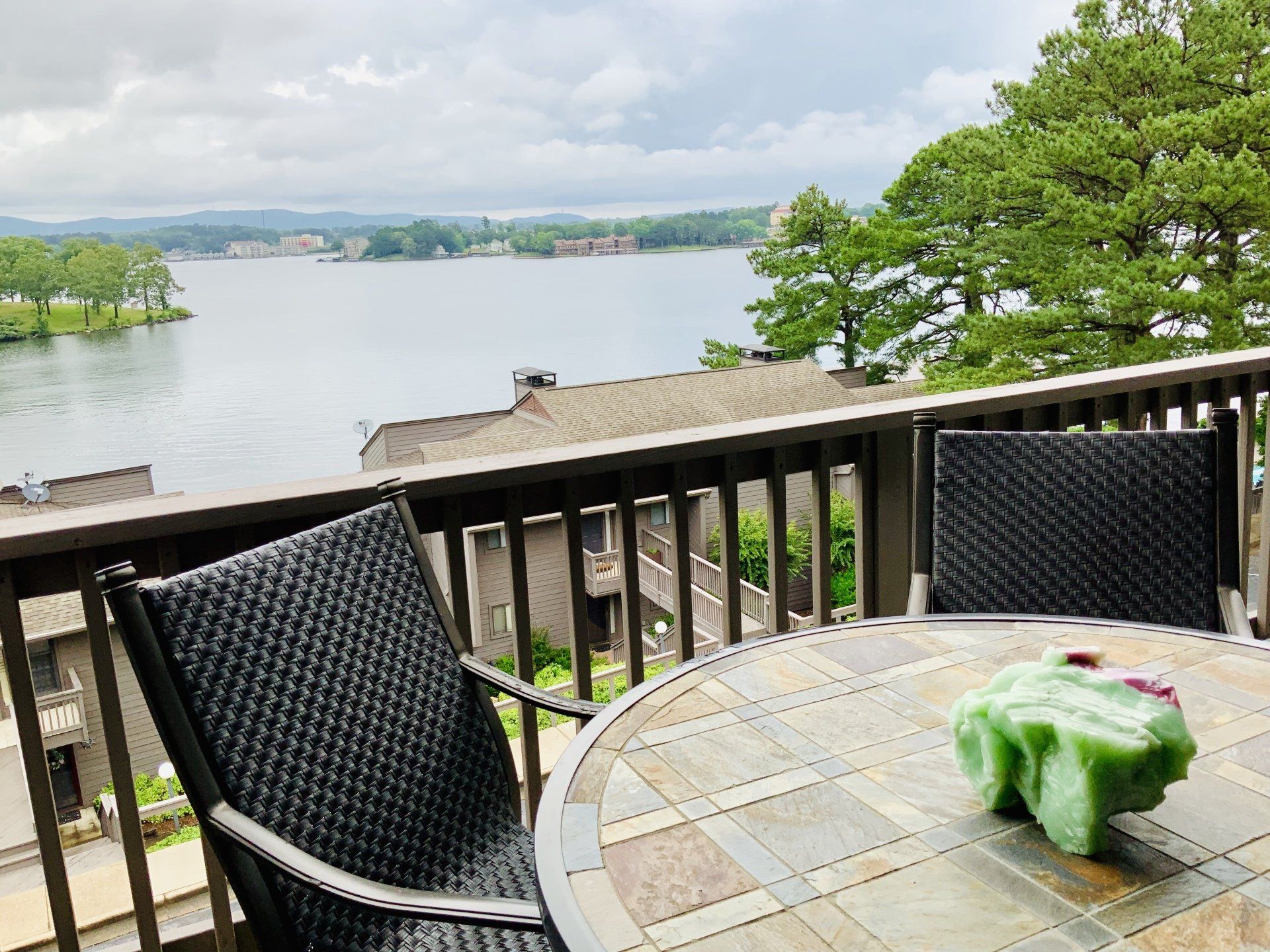 A table and chairs on a balcony overlooking a lake.