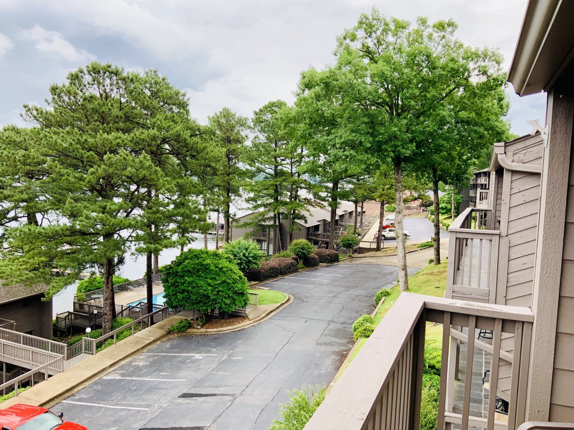 A balcony with a view of a parking lot and trees