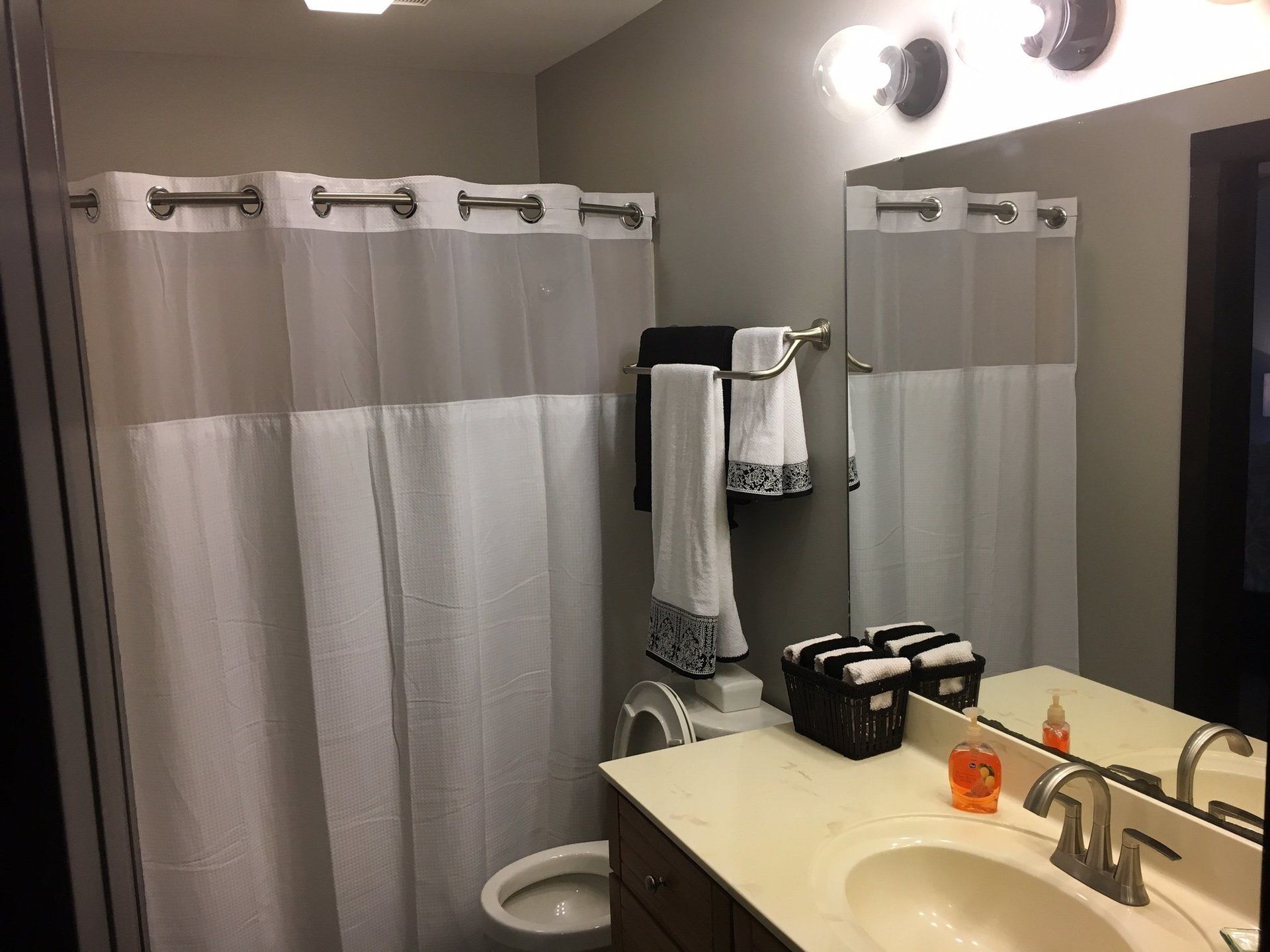 A bathroom with a sink , toilet , shower curtain and mirror.