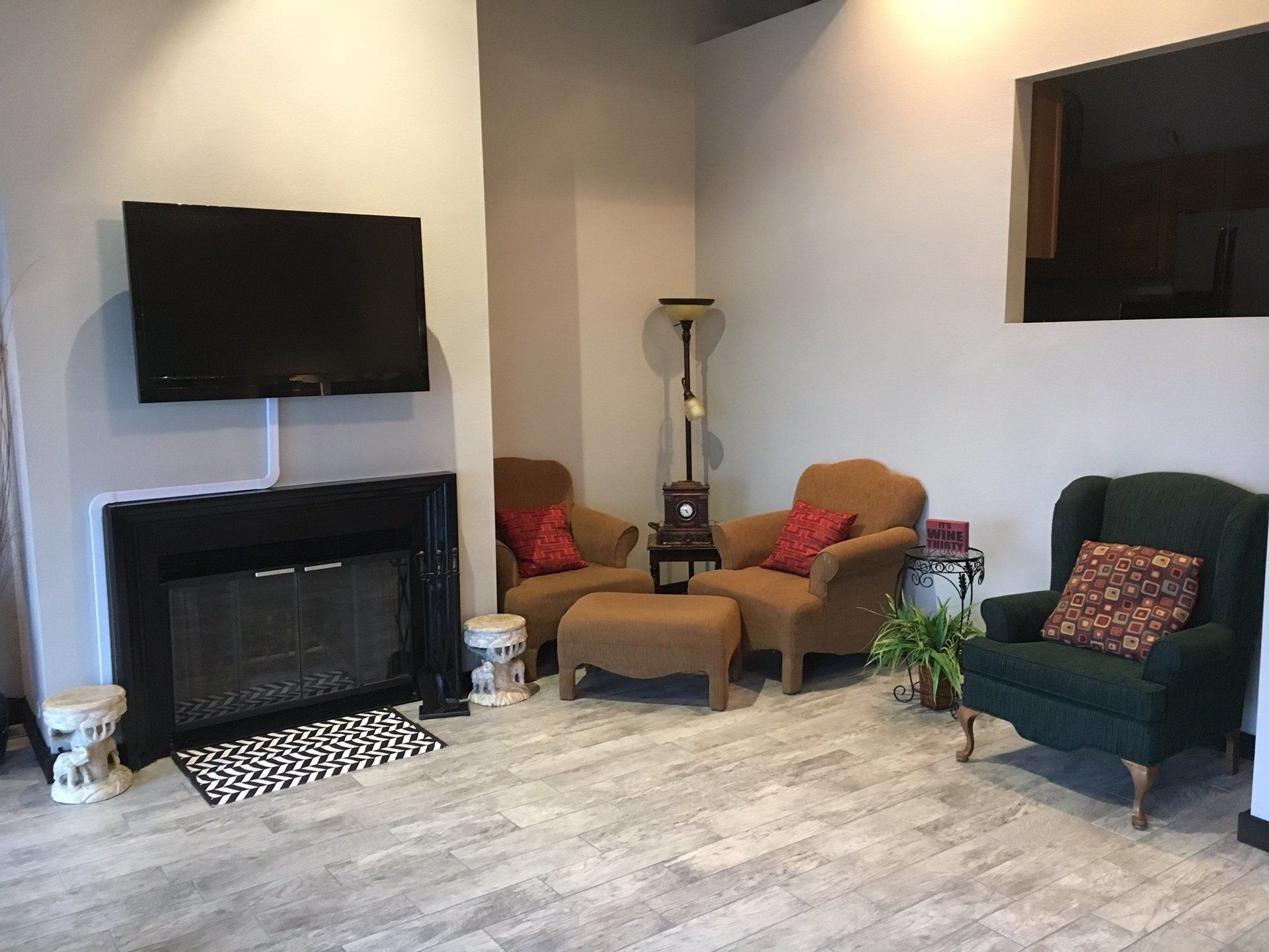 A living room with a fireplace , chairs and a flat screen tv.