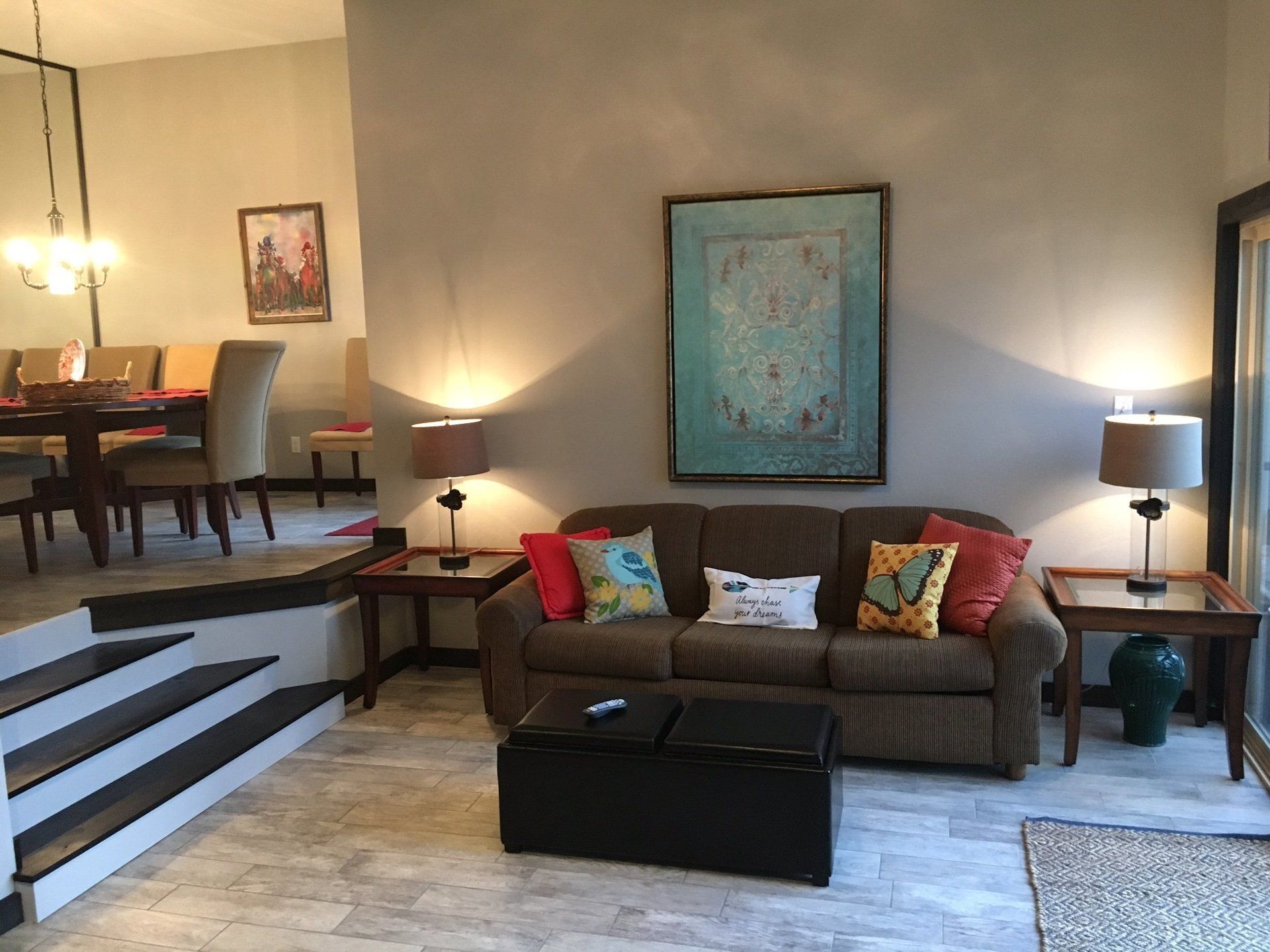 A living room with a couch and stairs leading to the dining room