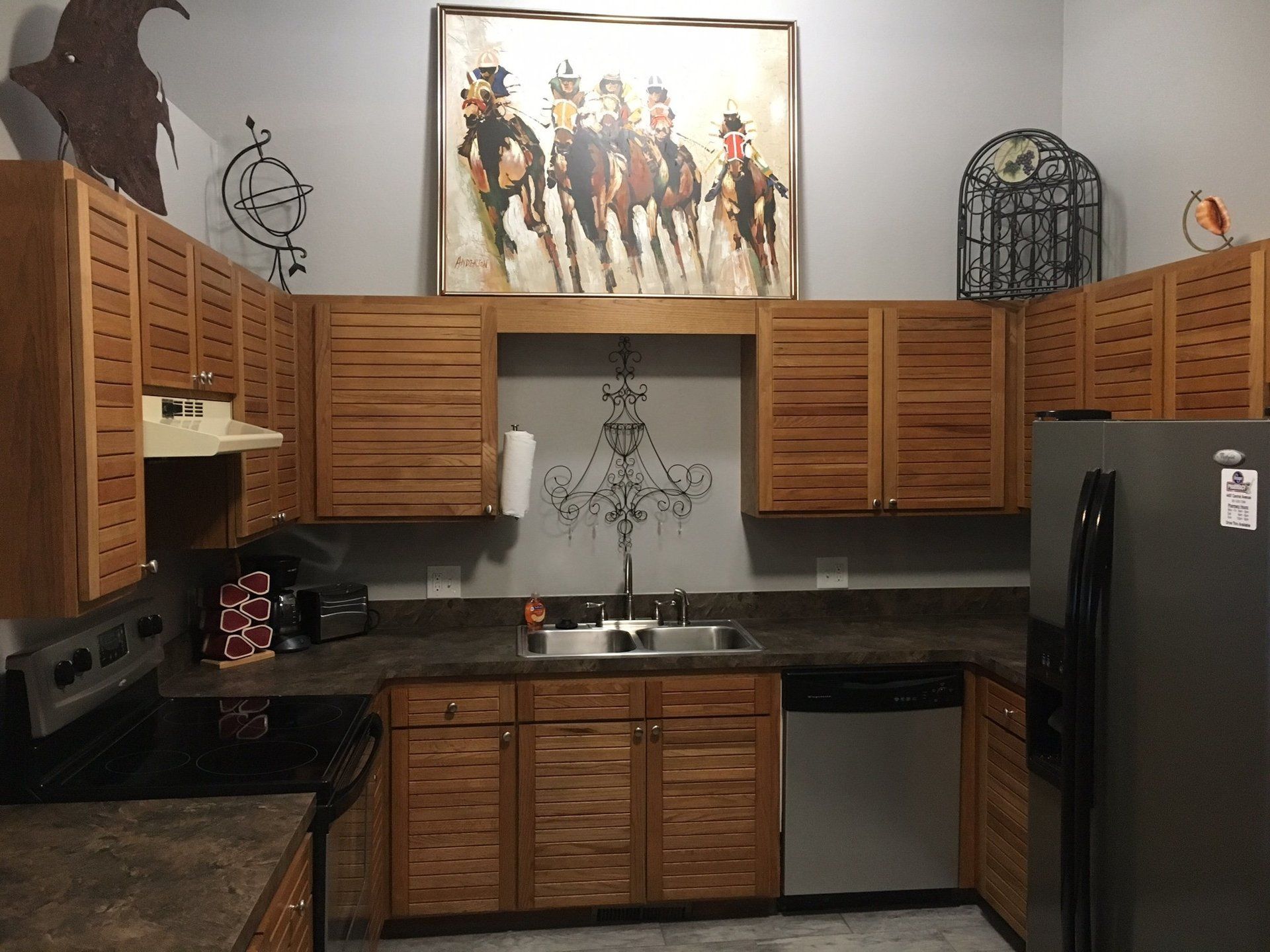 A kitchen with a picture of horses on the wall above the sink
