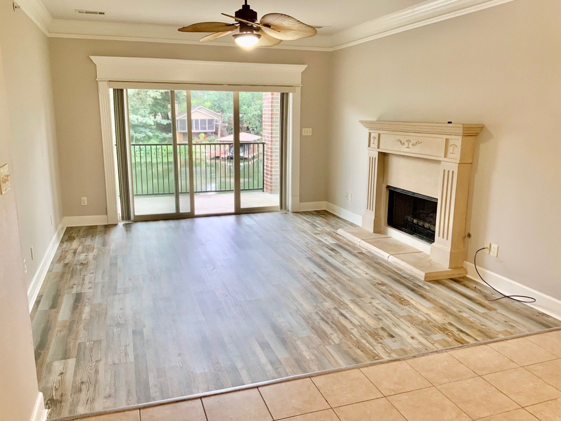 An empty living room with a fireplace and sliding glass doors.