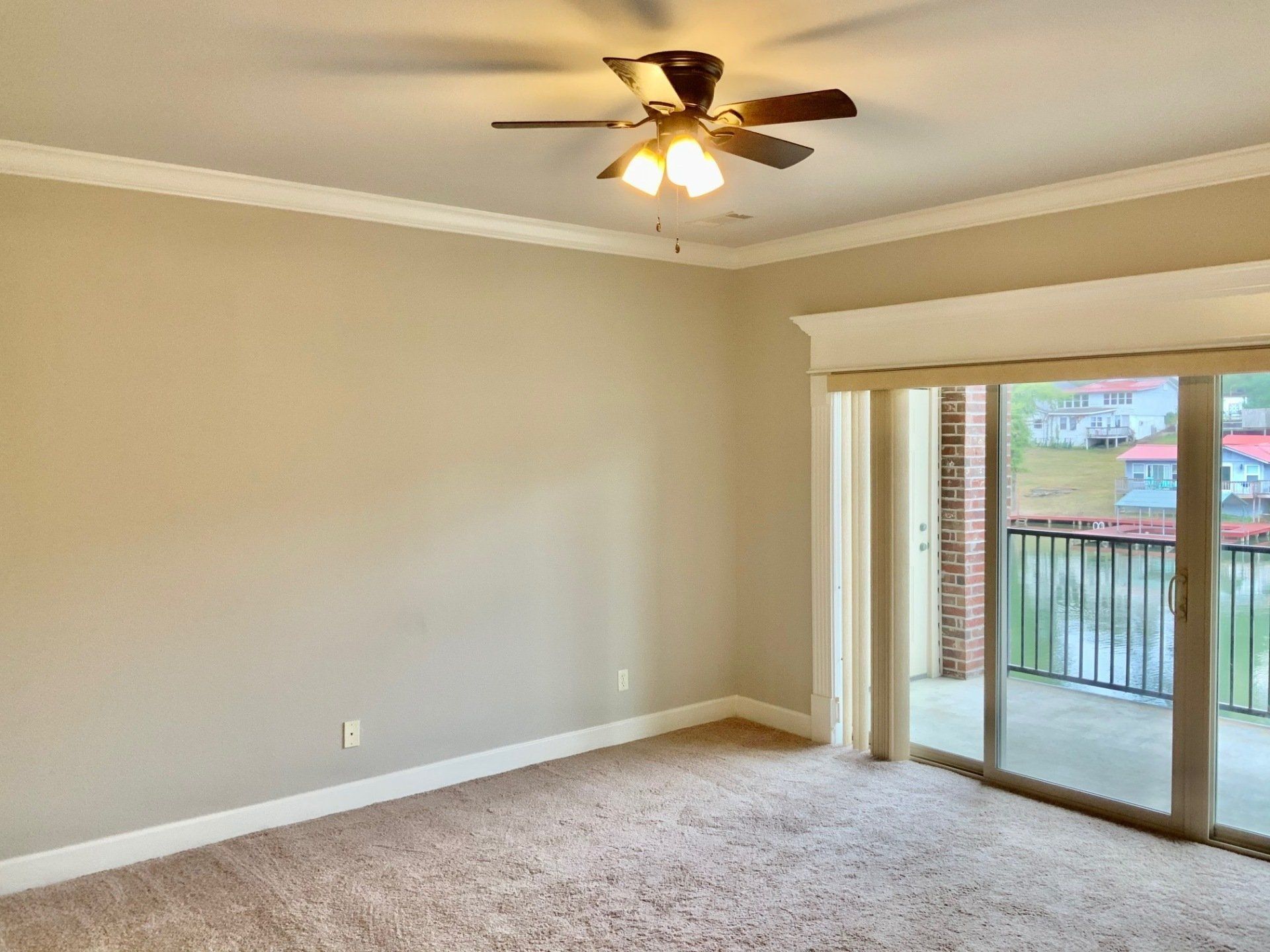 An empty room with a ceiling fan and sliding glass doors