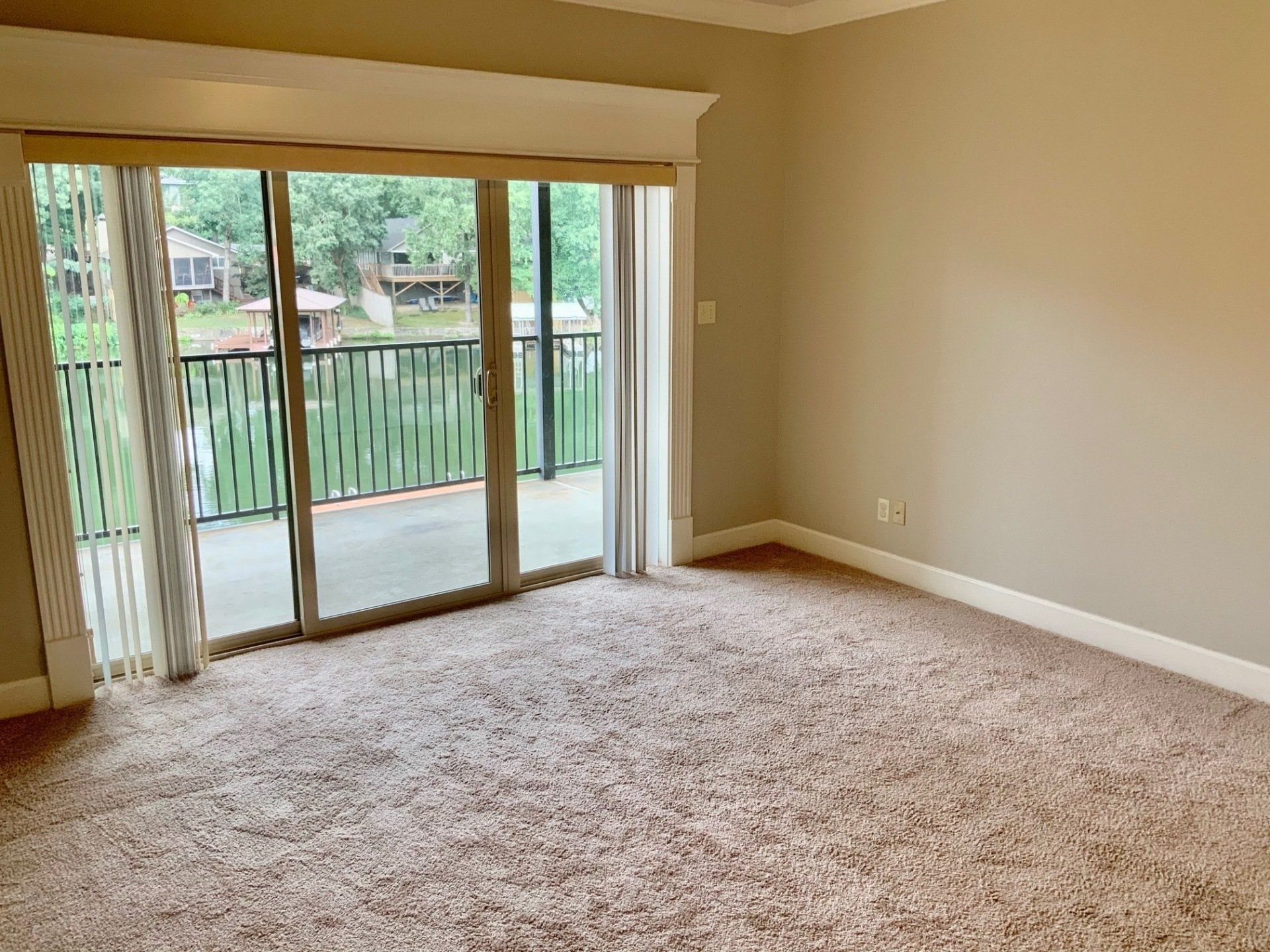 An empty living room with sliding glass doors leading to a balcony.
