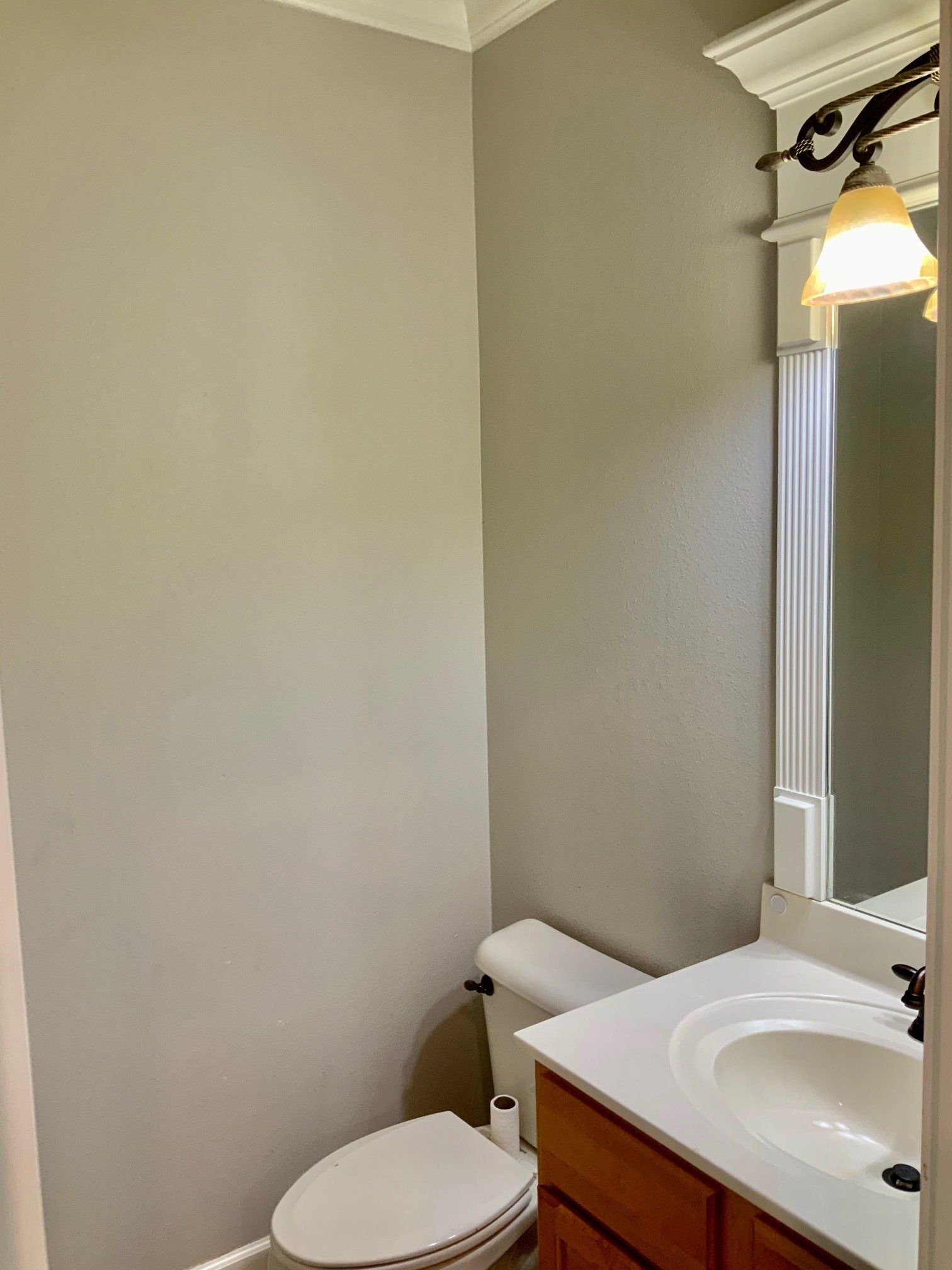 A bathroom with a toilet , sink and mirror.