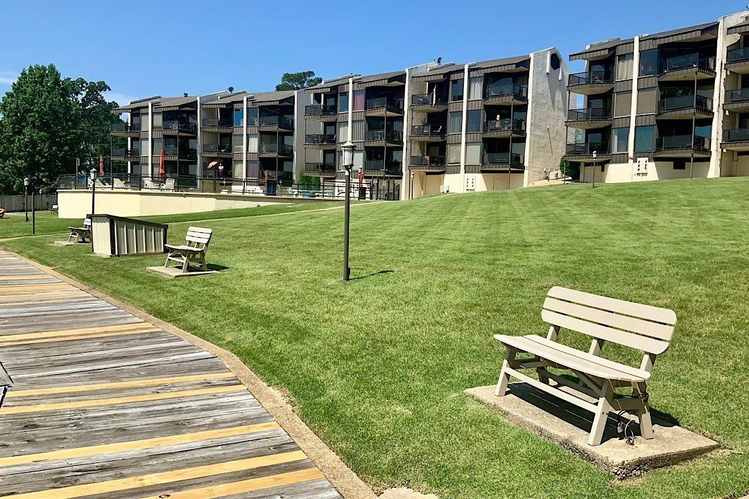 A bench is sitting in the grass in front of a building.