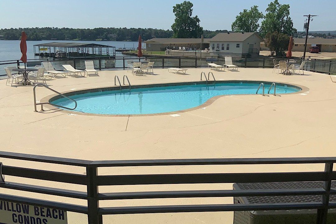 A large swimming pool is surrounded by a fence and chairs.