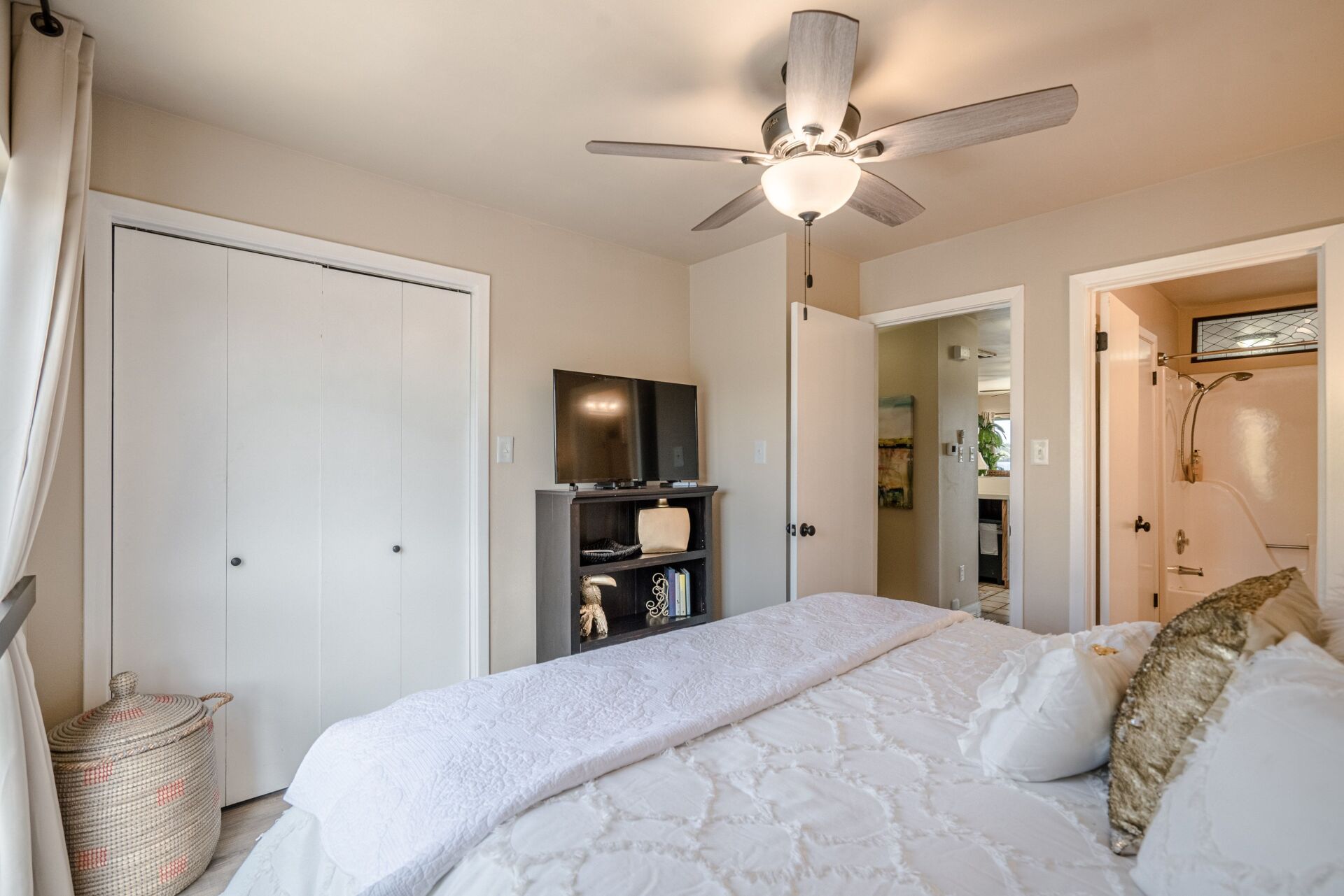 A bedroom with a bed , ceiling fan , television and closet.