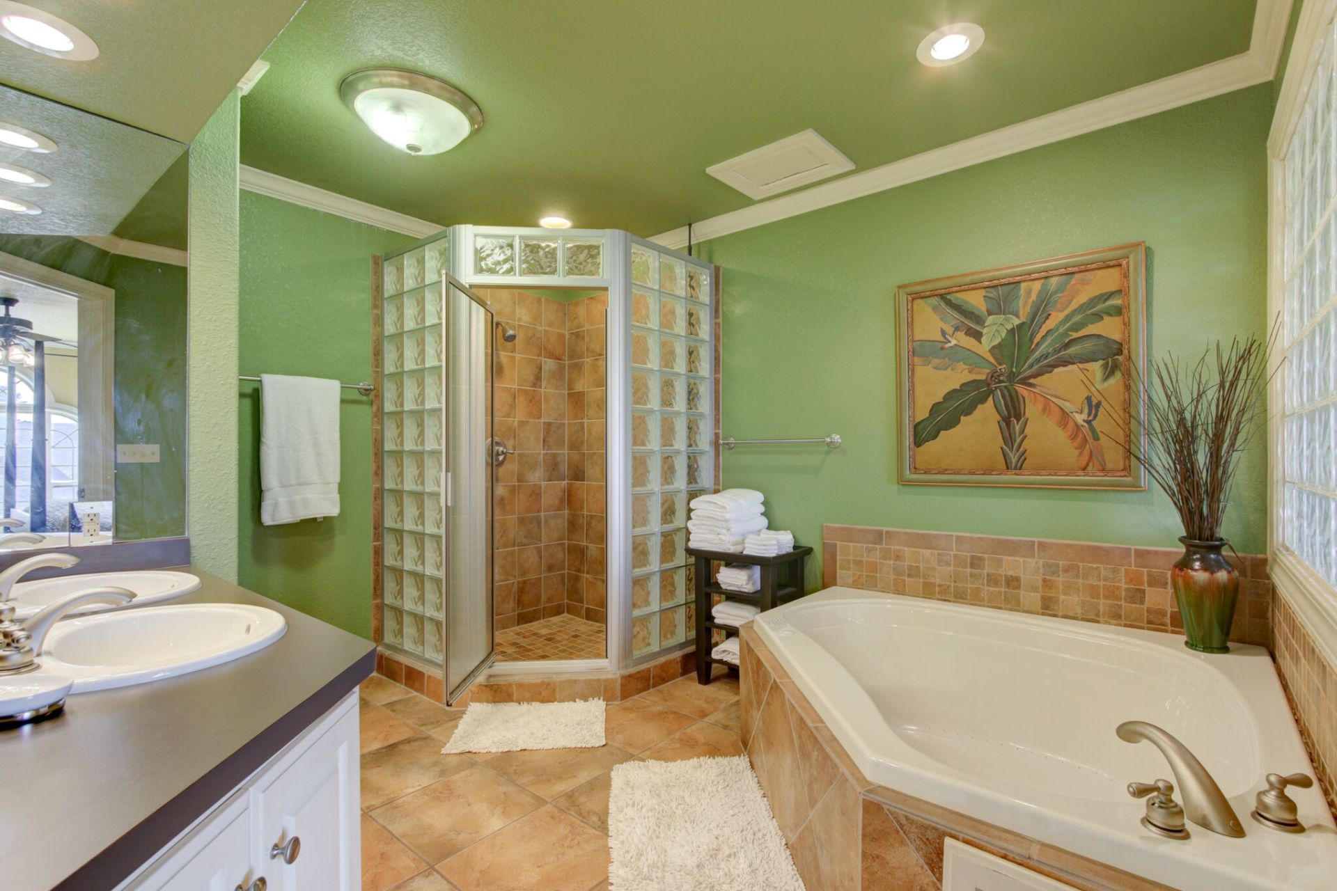 A bathroom with green walls , a tub , a sink , and a walk in shower.