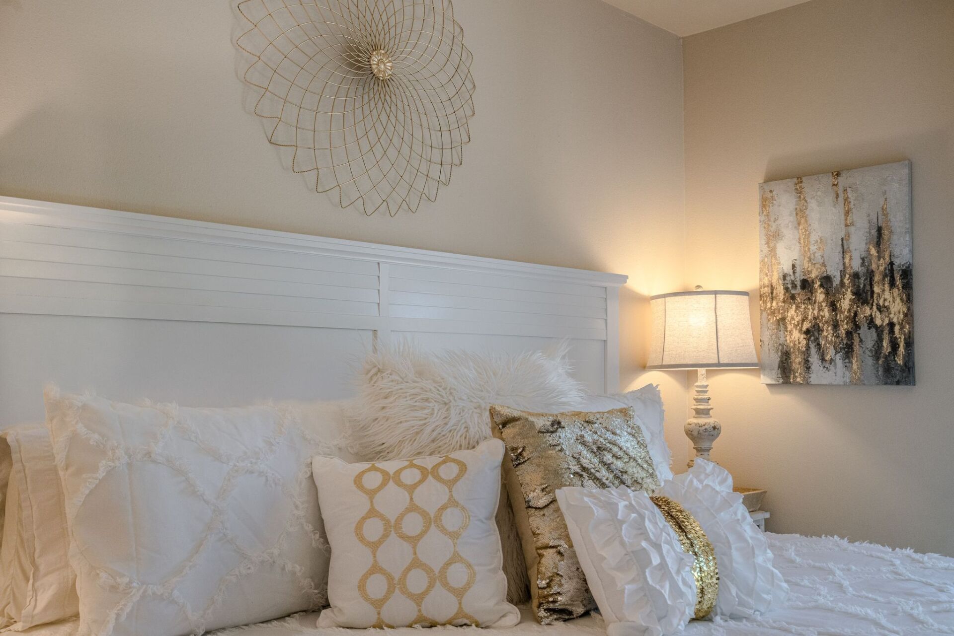 A bedroom with a bed , pillows , lamps and a painting on the wall.