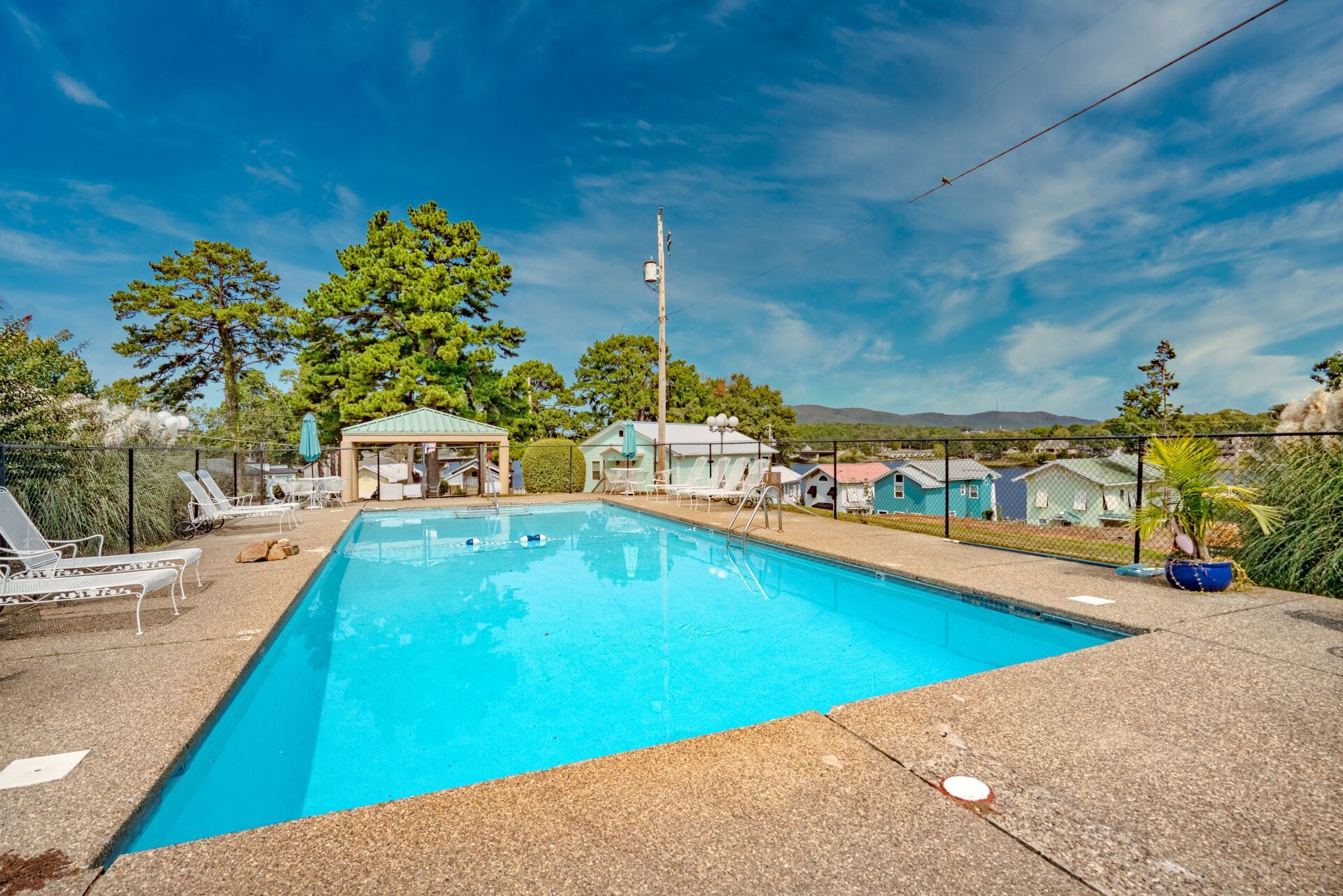 A large swimming pool is surrounded by chairs and a gazebo.