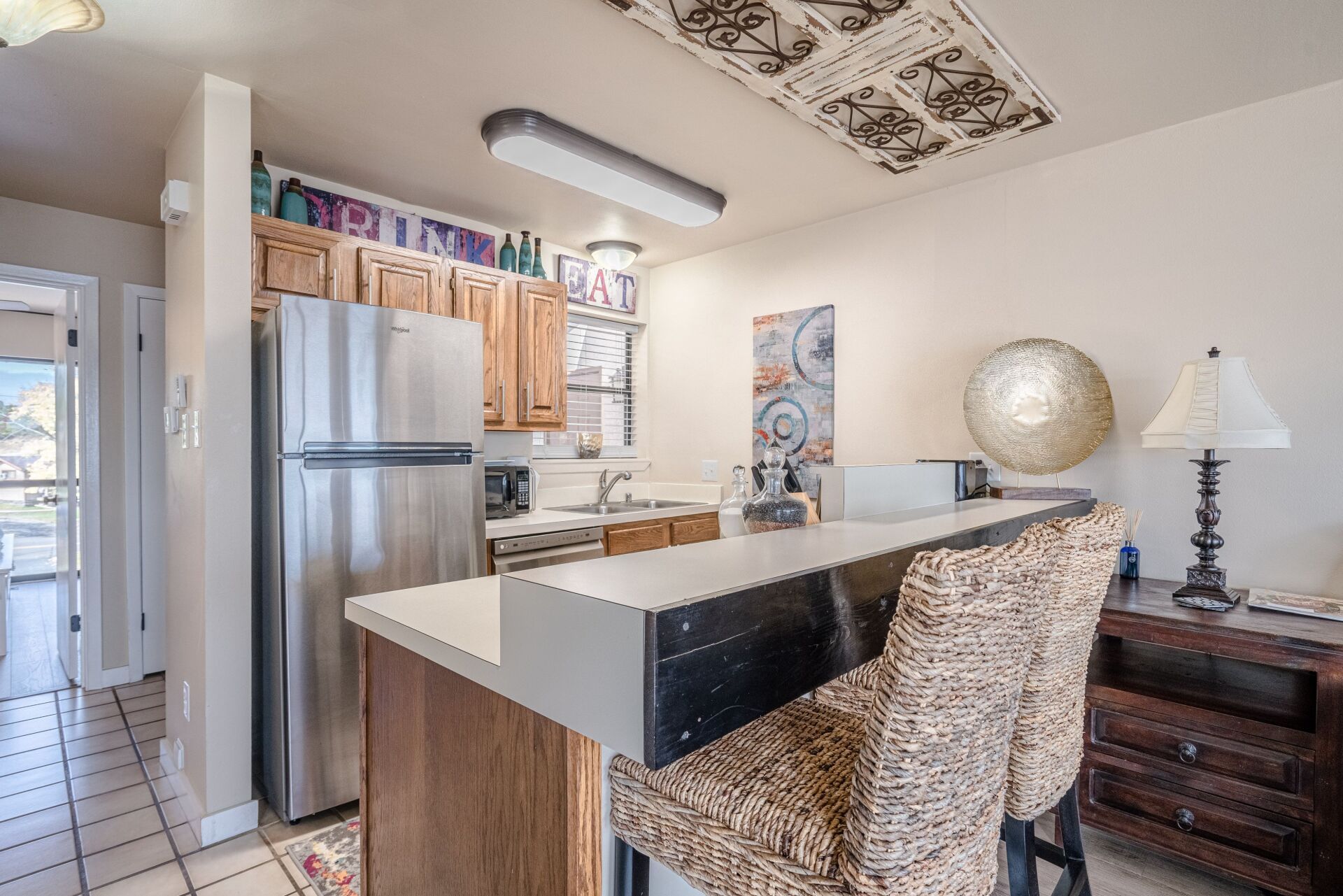 A kitchen with a refrigerator , dishwasher , sink , and bar.