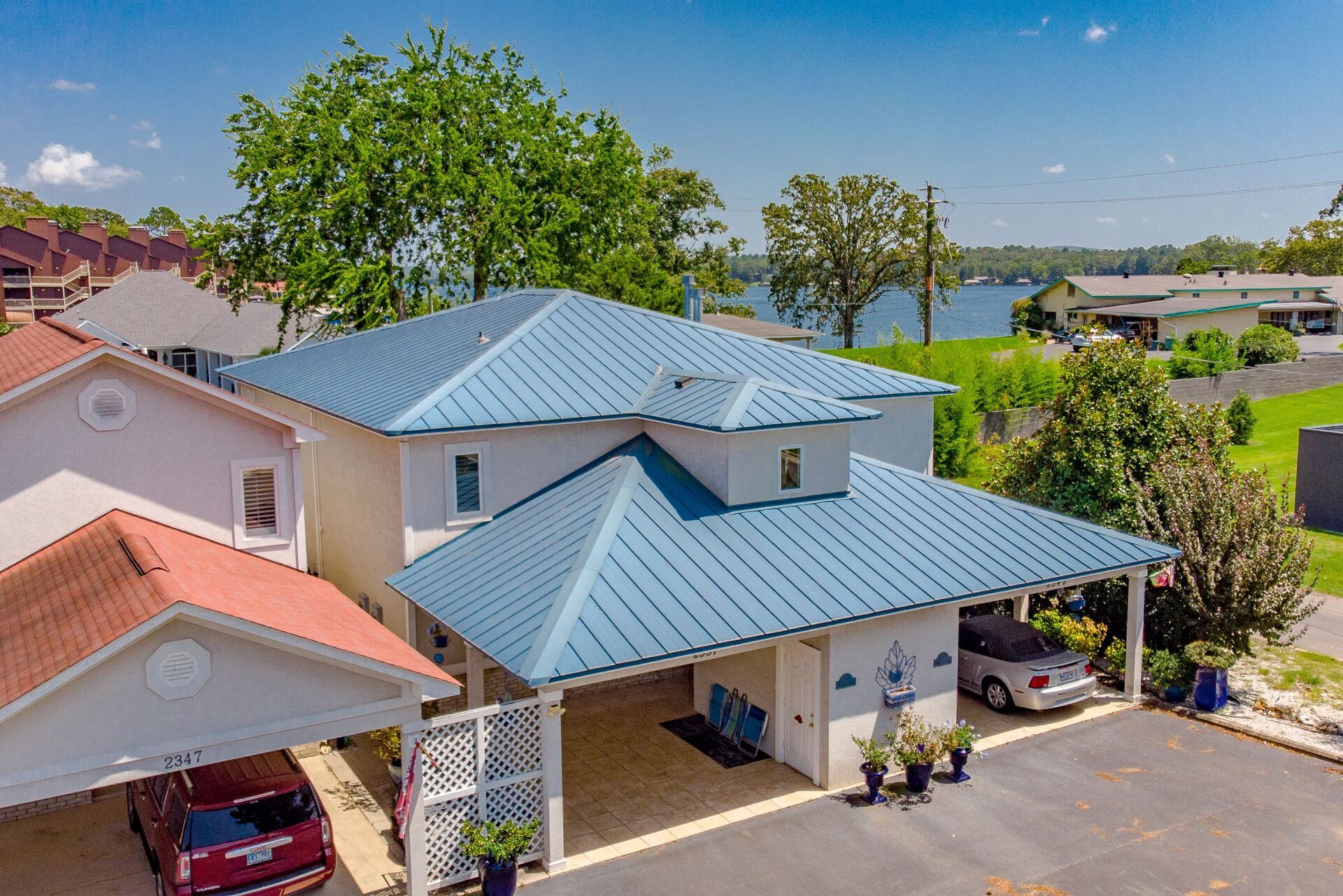 An aerial view of a house with a blue roof and a car parked in front of it.