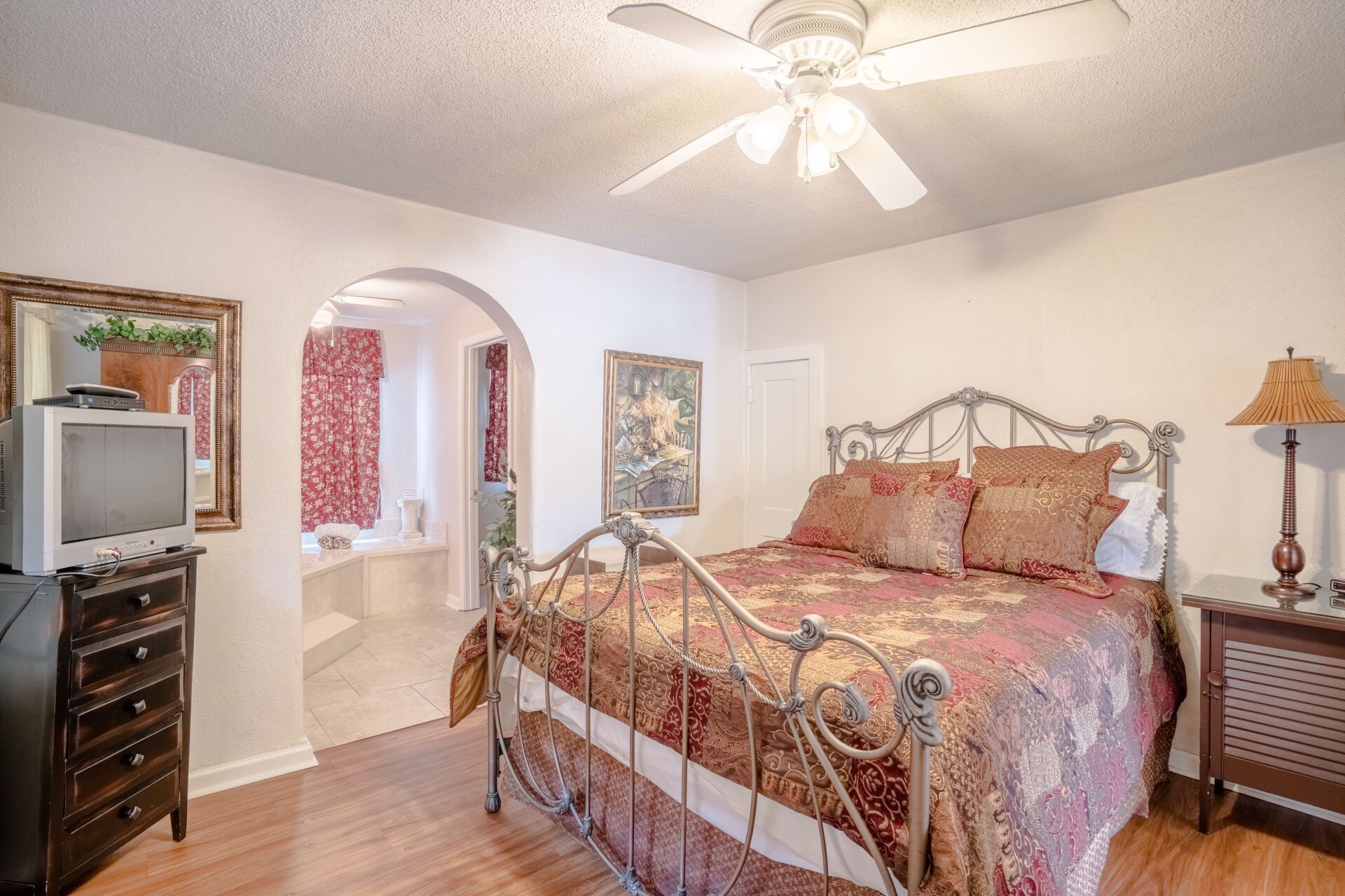 A bedroom with a king size bed and a ceiling fan